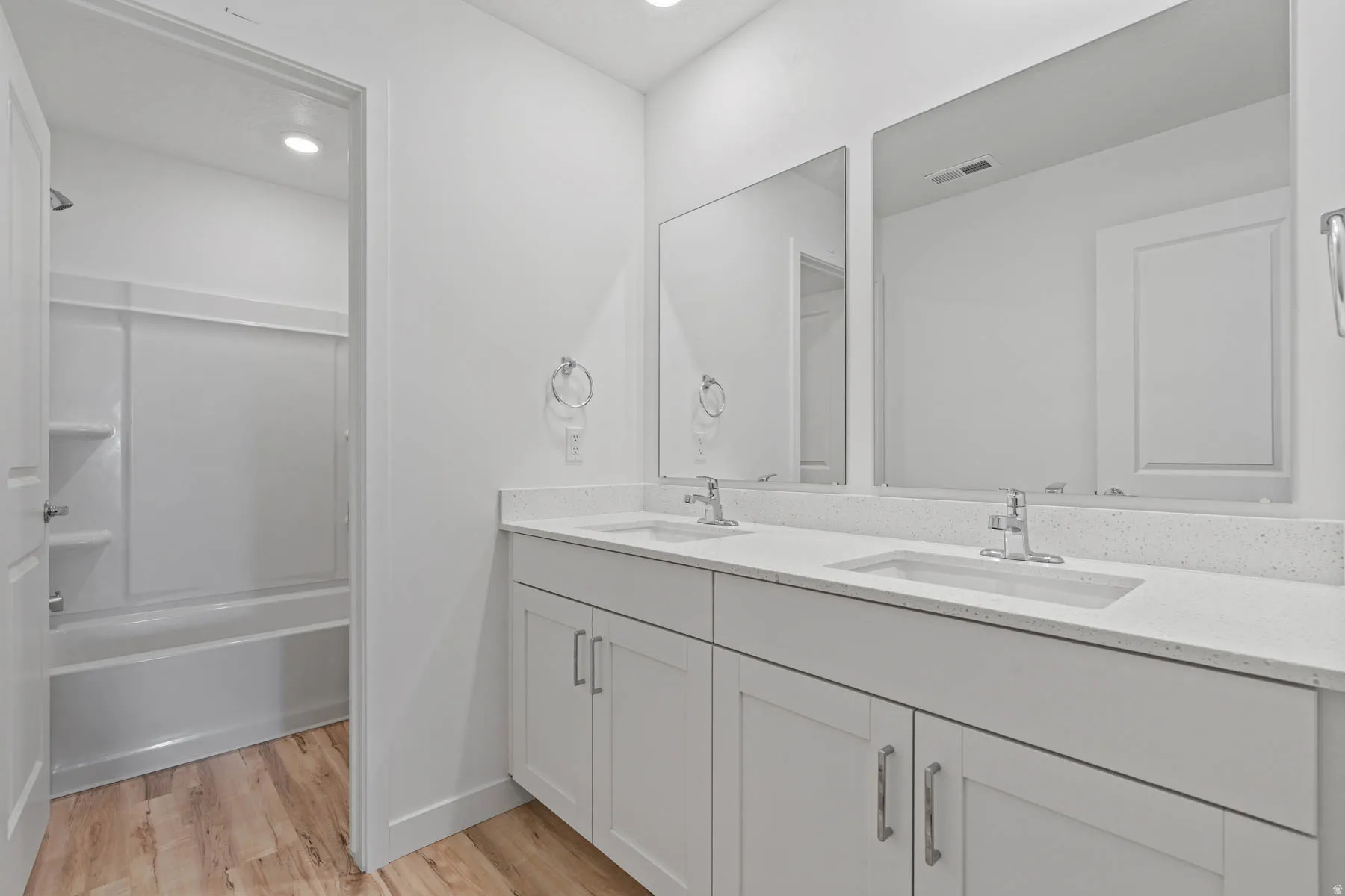 Dual vanity with white cabinetry and integrated sinks, complemented by a solid surface countertop and two rectangular mirrors