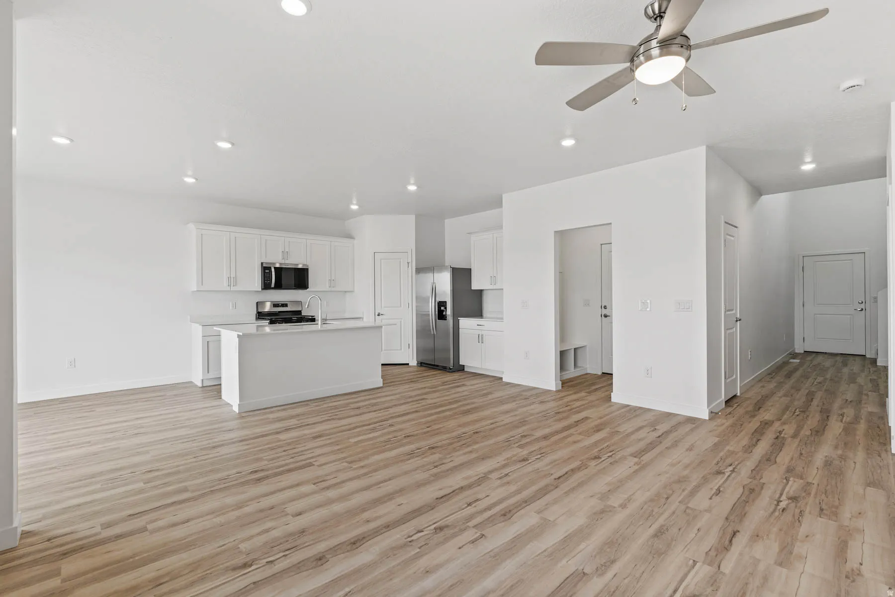 Open-concept living area featuring wood-finish flooring, recessed lighting, and a contemporary ceiling fan