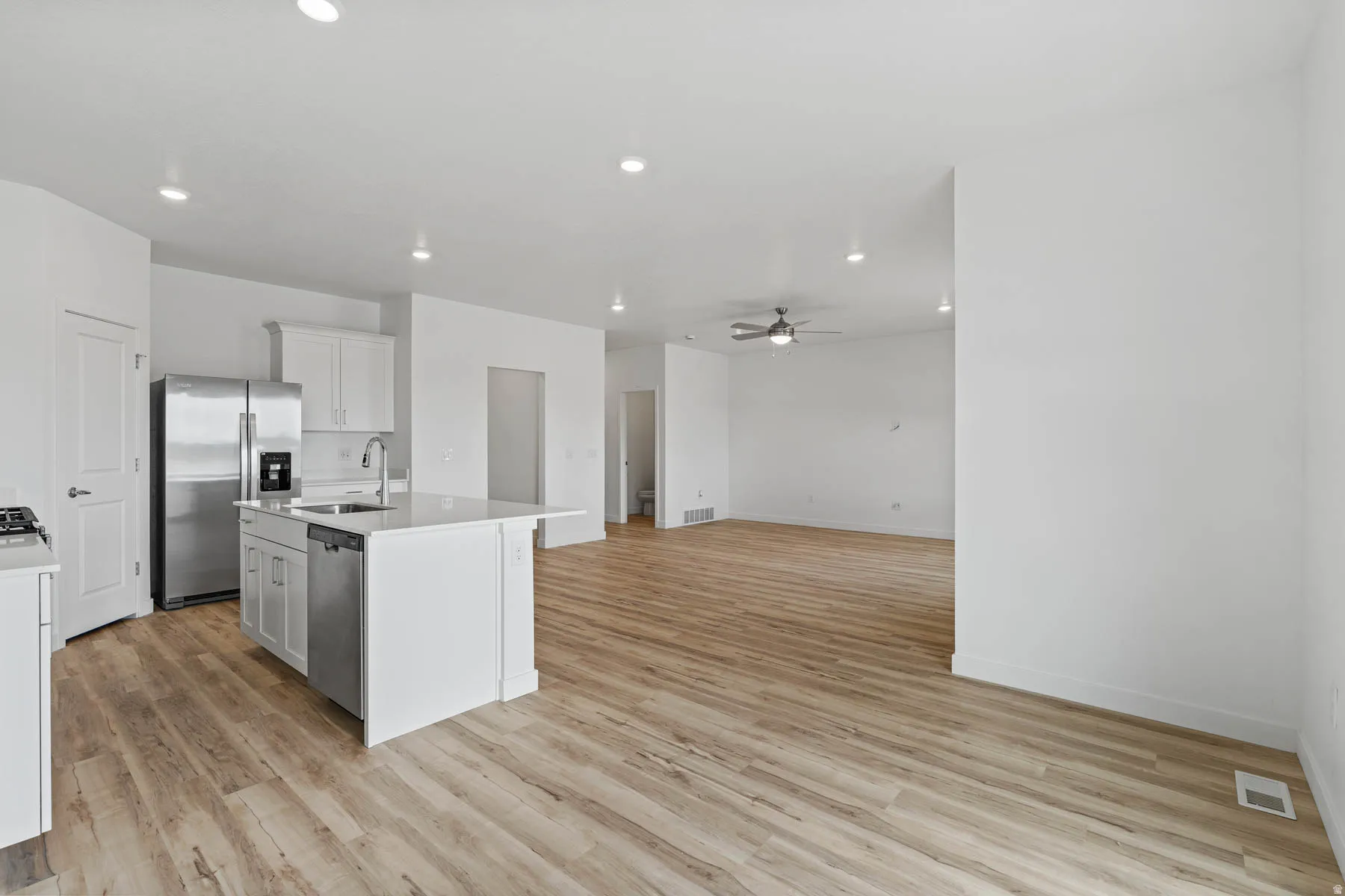 Open-concept living area featuring wood-finish flooring throughout, recessed lighting, and a contemporary ceiling fan