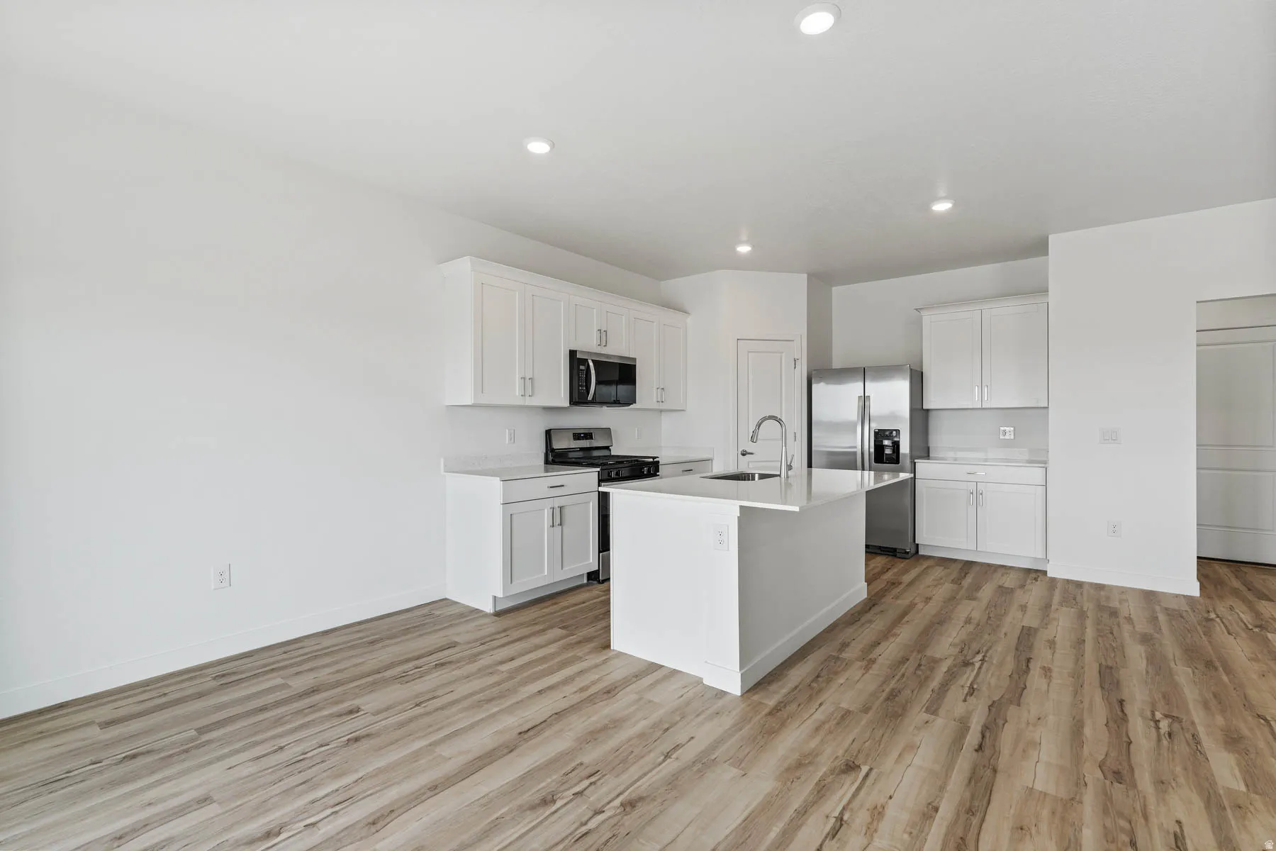 Modern kitchen with white cabinetry and an island featuring a sink