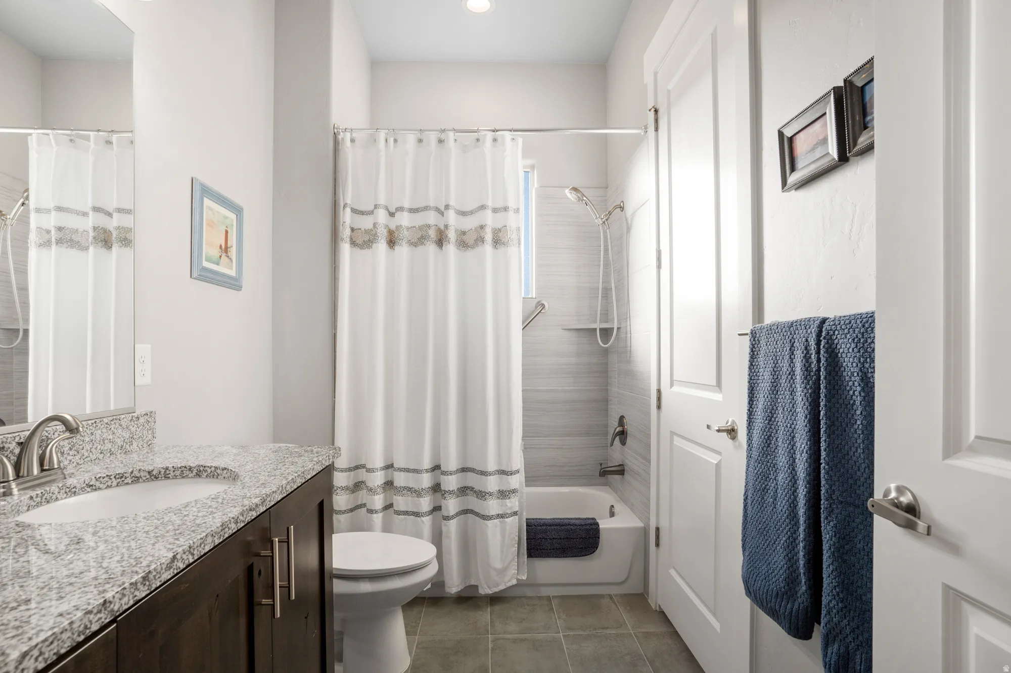 Full bathroom featuring a single vanity with stone countertop, undermount sink, and brushed nickel faucet