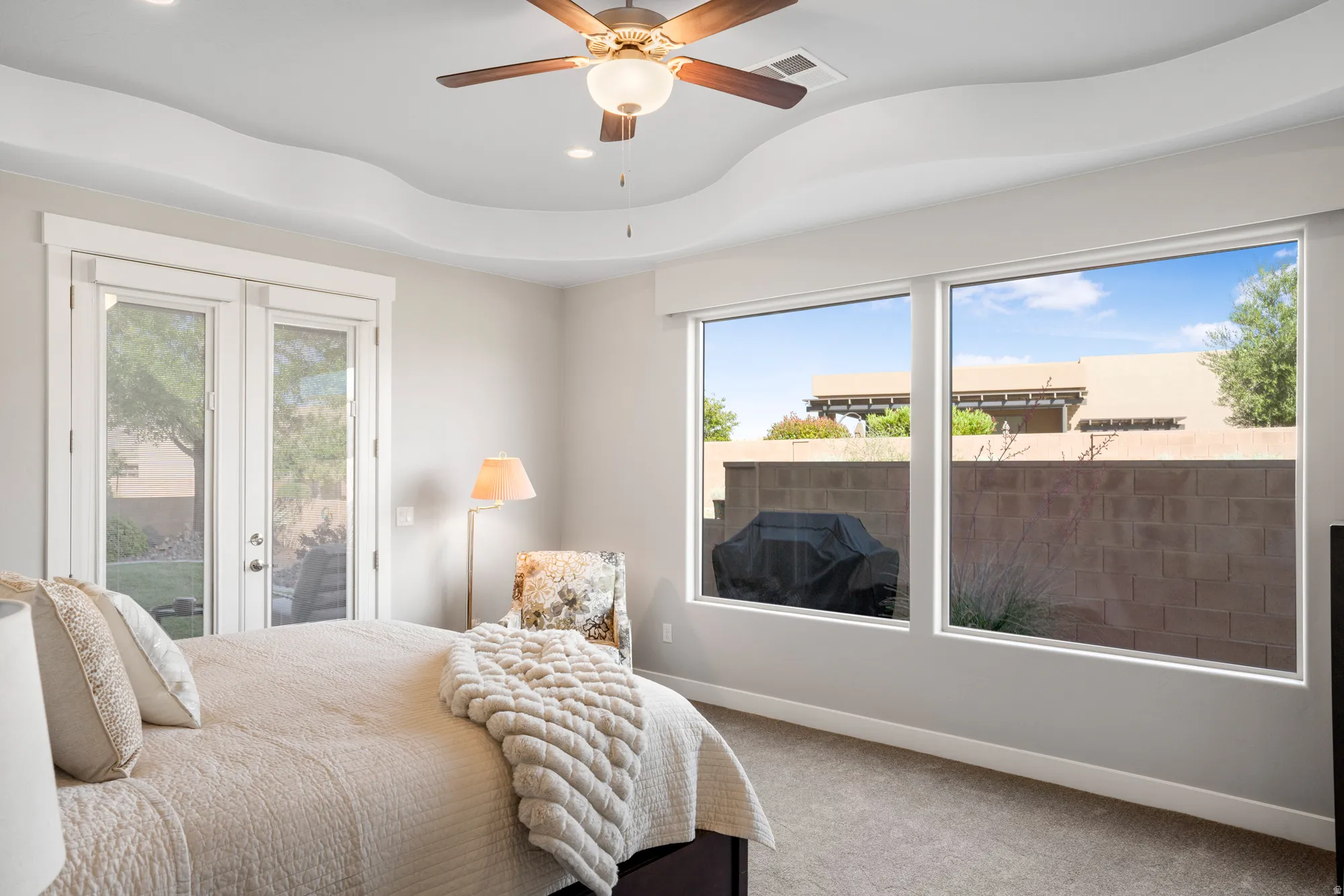 Interior space featuring a decorative tray ceiling with a ceiling fan, carpet flooring, and white trim