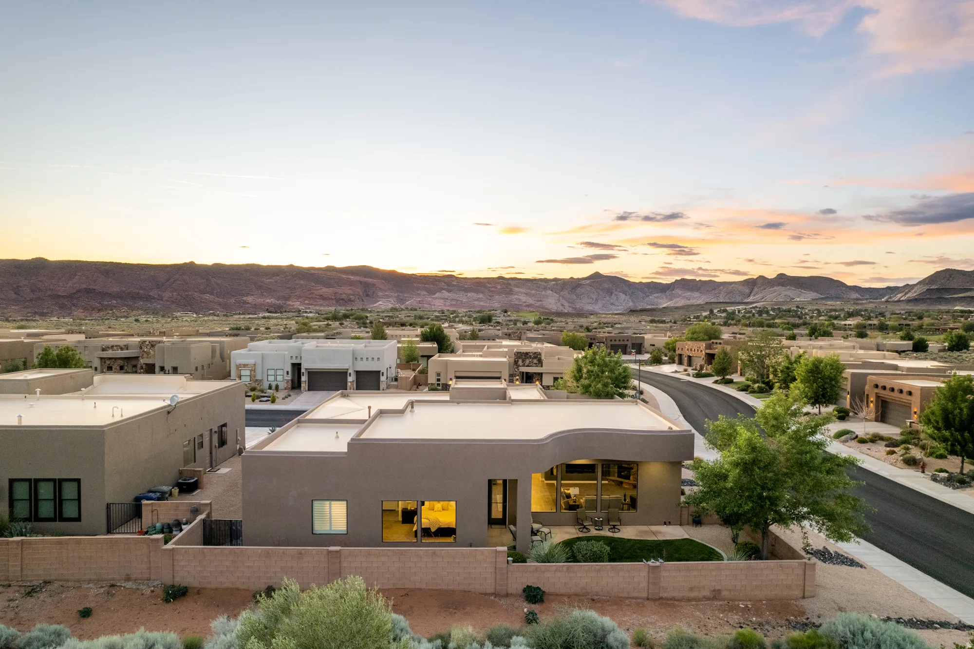 Contemporary stucco residence featuring a flat roofline, integrated landscaping, and a walled perimeter