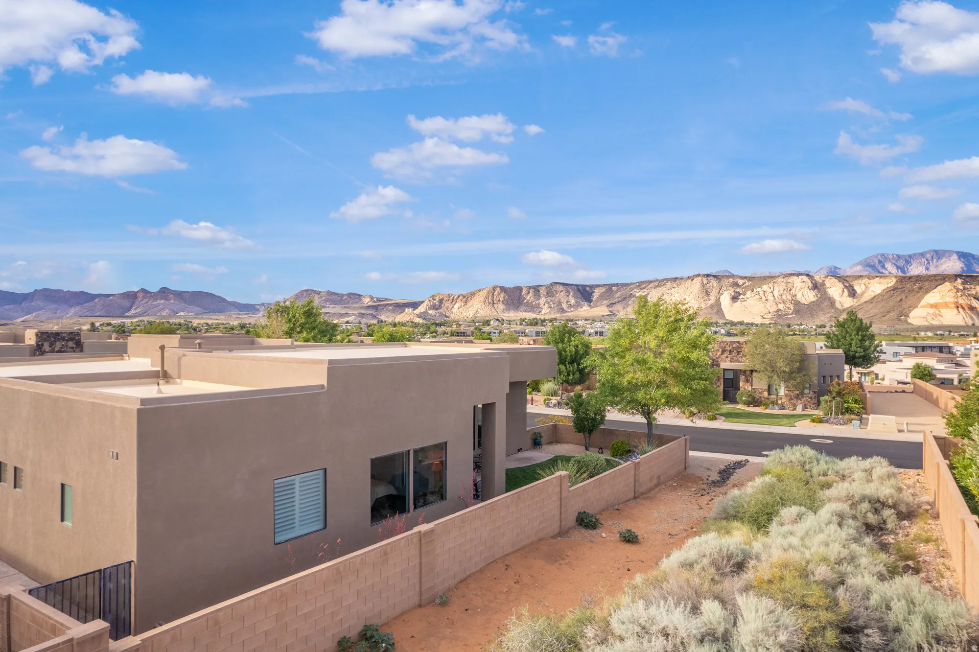 Modern stucco exterior featuring a flat roofline, integrated windows, and a private walled yard