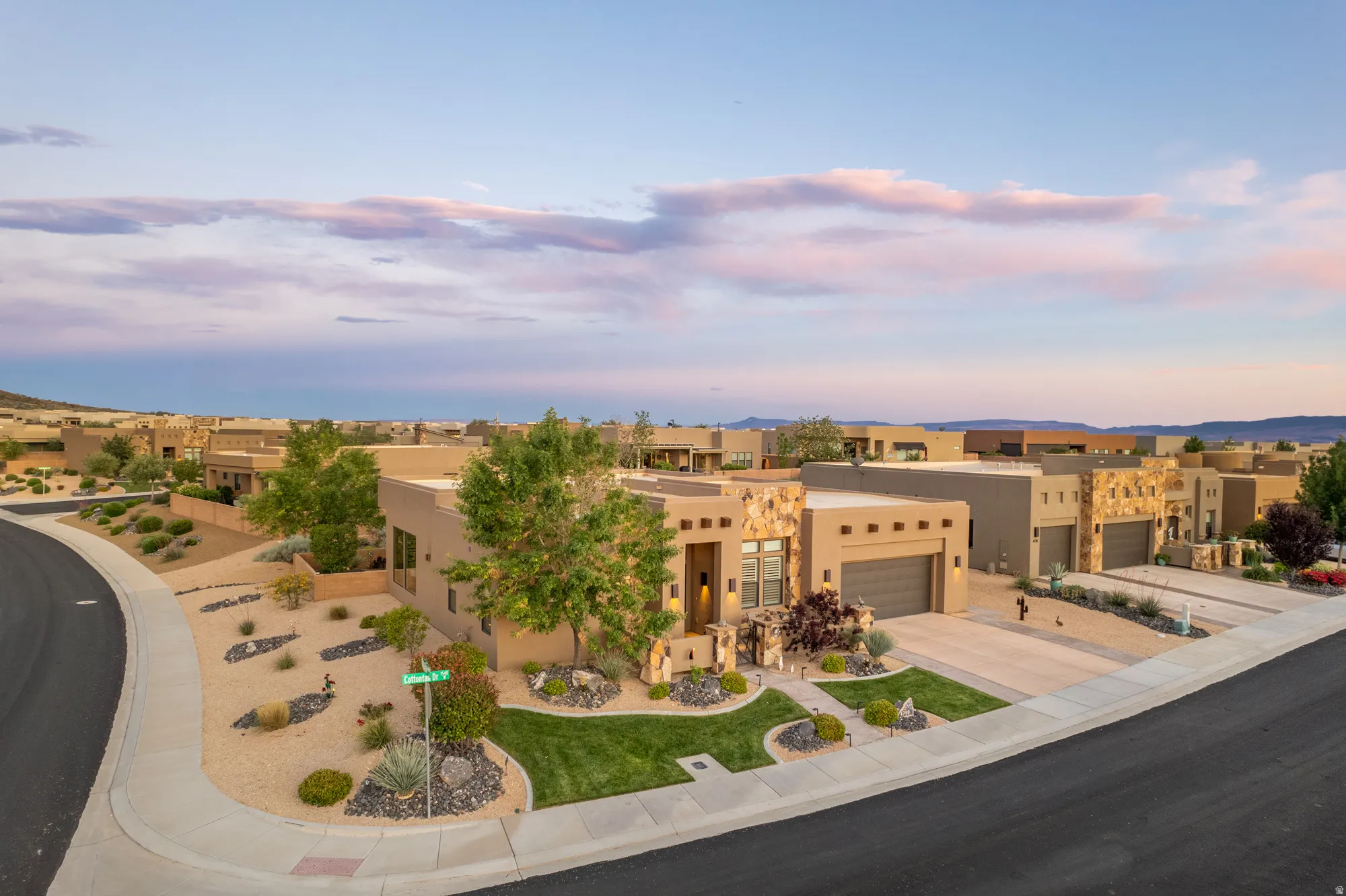 Modern stucco exterior with stacked stone accents, a multi-car garage, and a paver driveway