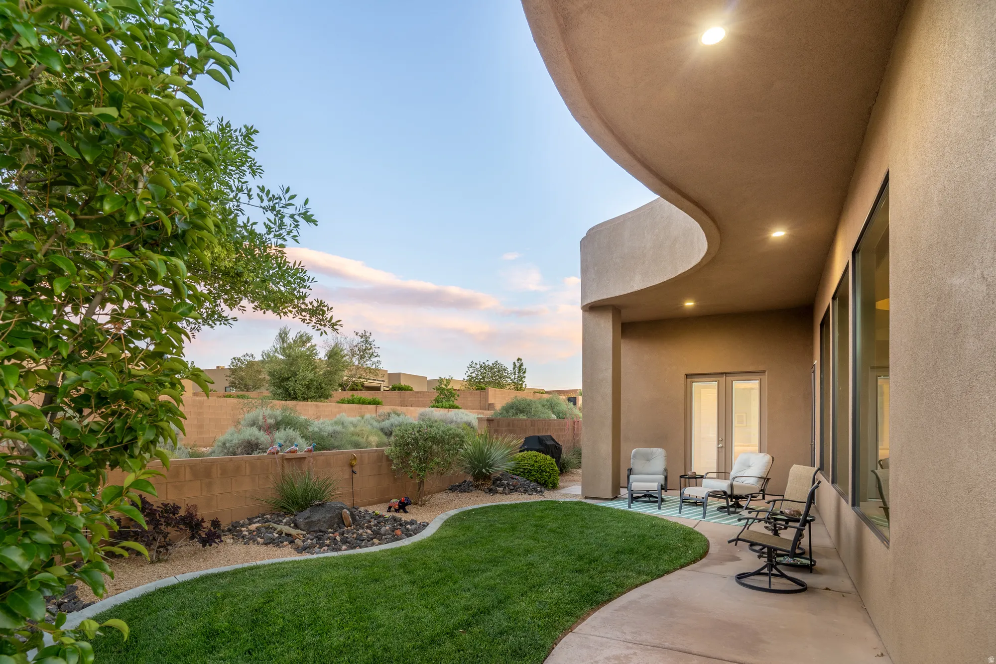 Spacious backyard with a curved concrete patio, manicured lawn, and desert-inspired landscaping