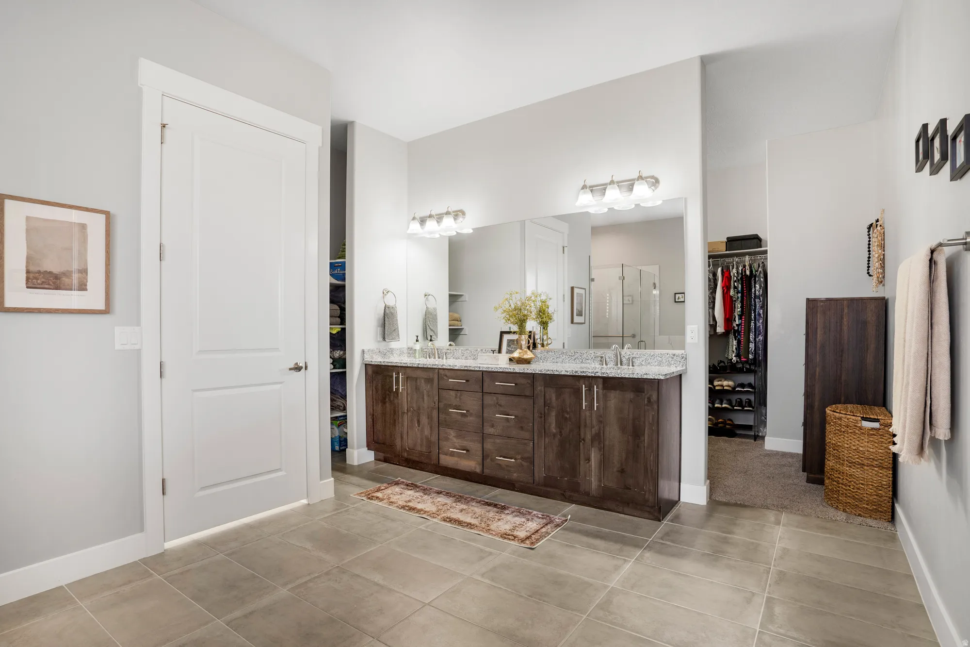 Spacious bathroom featuring a dual vanity with a granite countertop, integrated sinks, and ample storage cabinetry