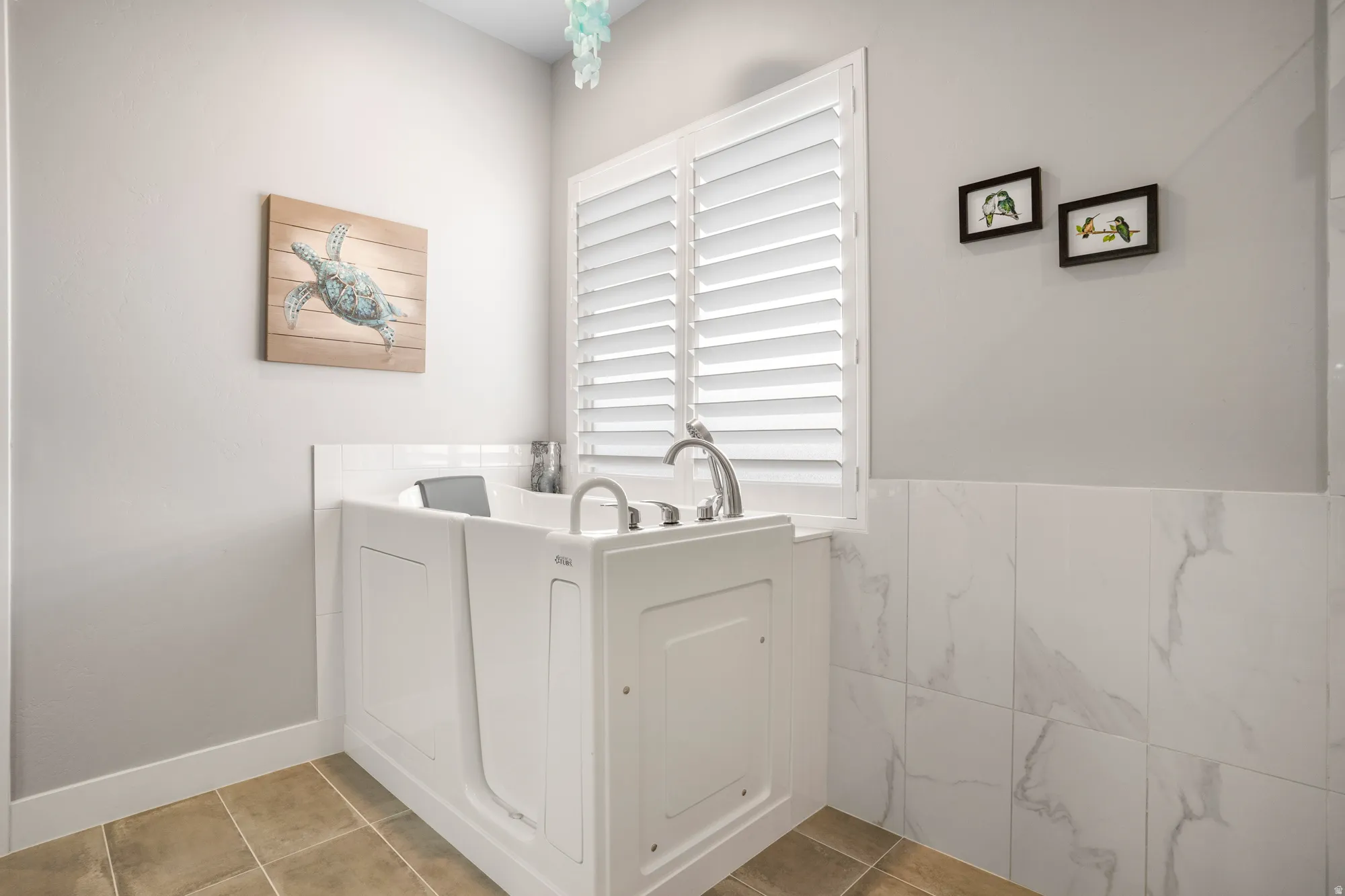 White walk-in tub featuring deck-mounted chrome fixtures, surrounded by light gray walls