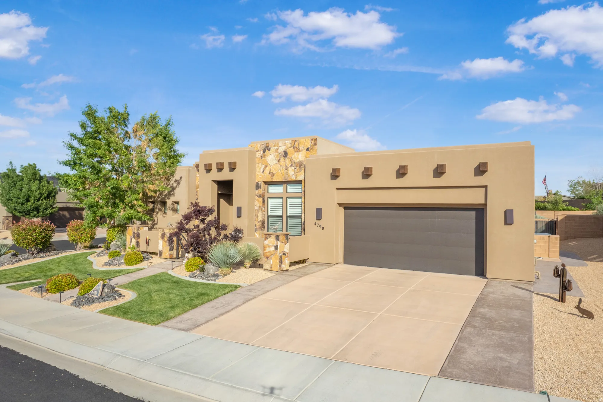 Southwestern-style exterior featuring a two-car garage, stone accents, and low-maintenance landscaping