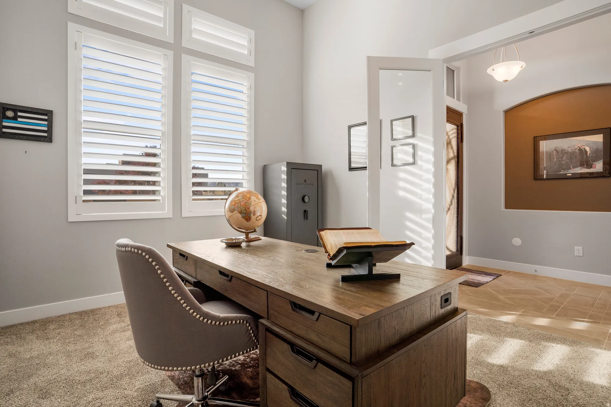 Office space featuring light gray walls, white plantation shutters, and a high vaulted ceiling