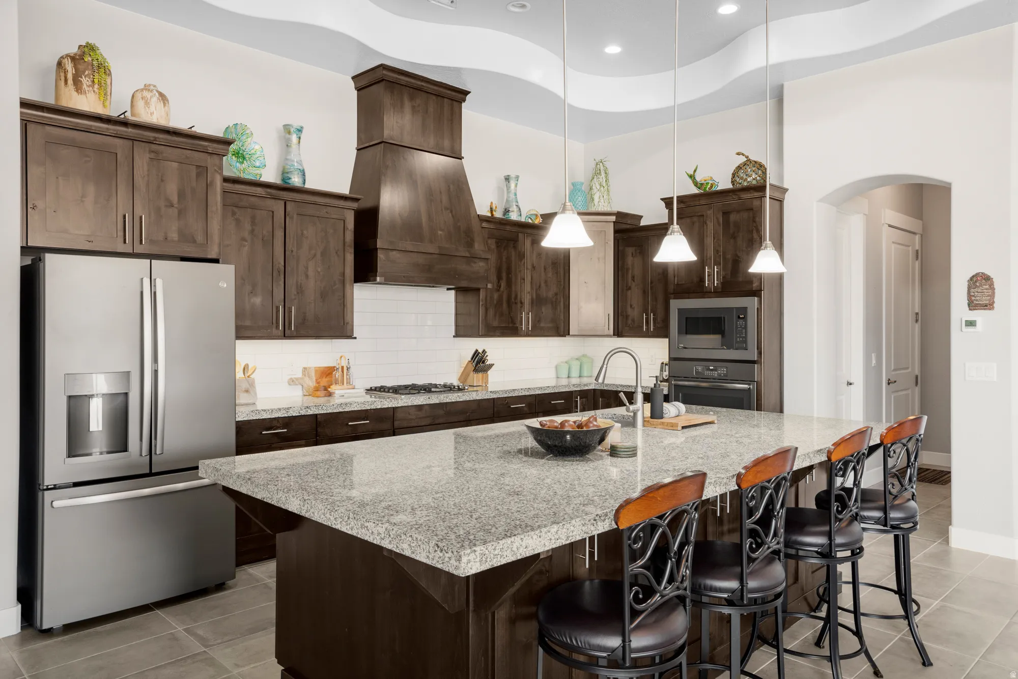 Gourmet kitchen with dark wood cabinetry, white subway tile backsplash, stainless steel appliances, and a built-in oven