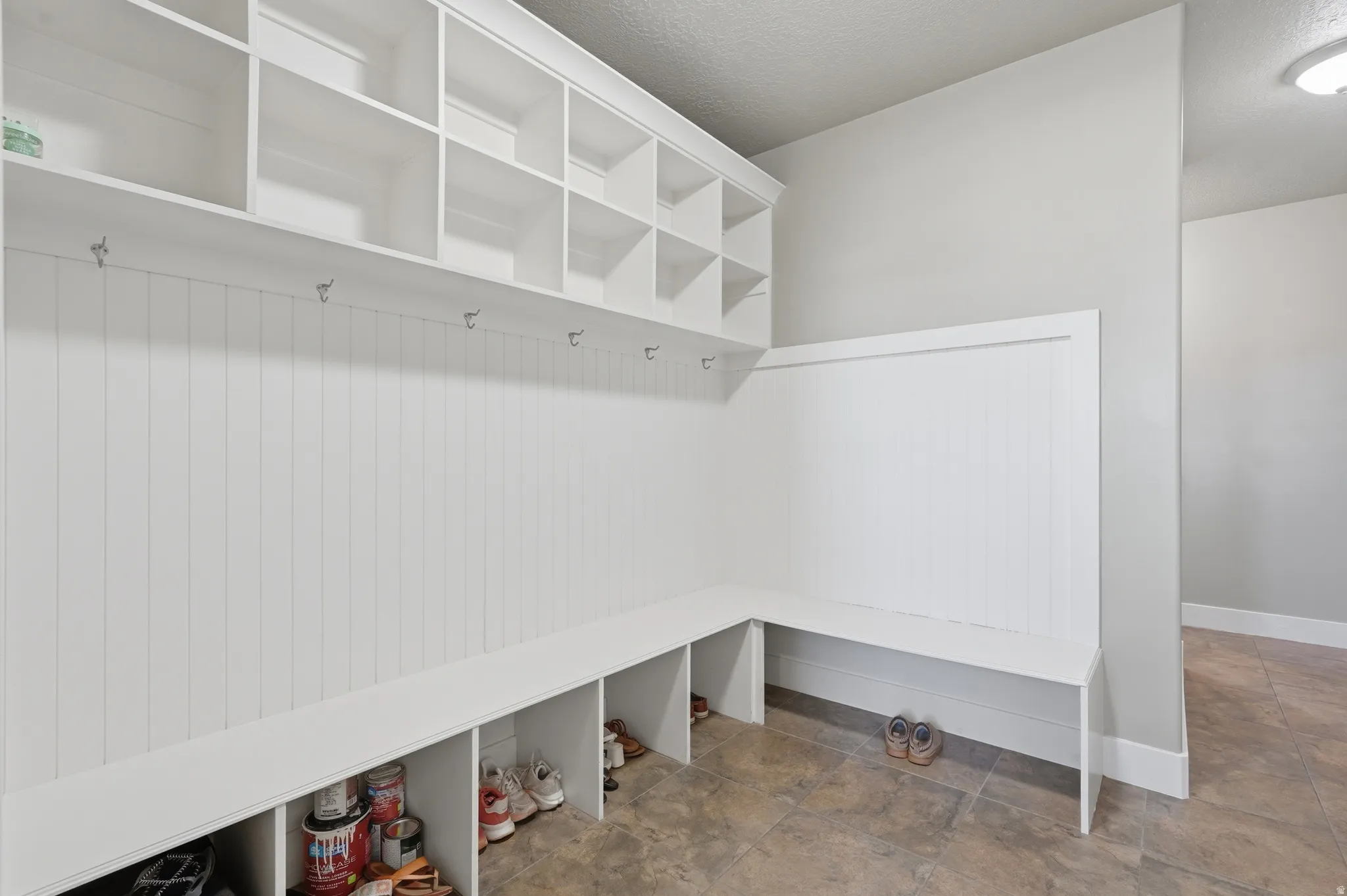 Built-in mudroom system featuring upper cubby storage, coat hooks, a bench, and lower shoe cubbies