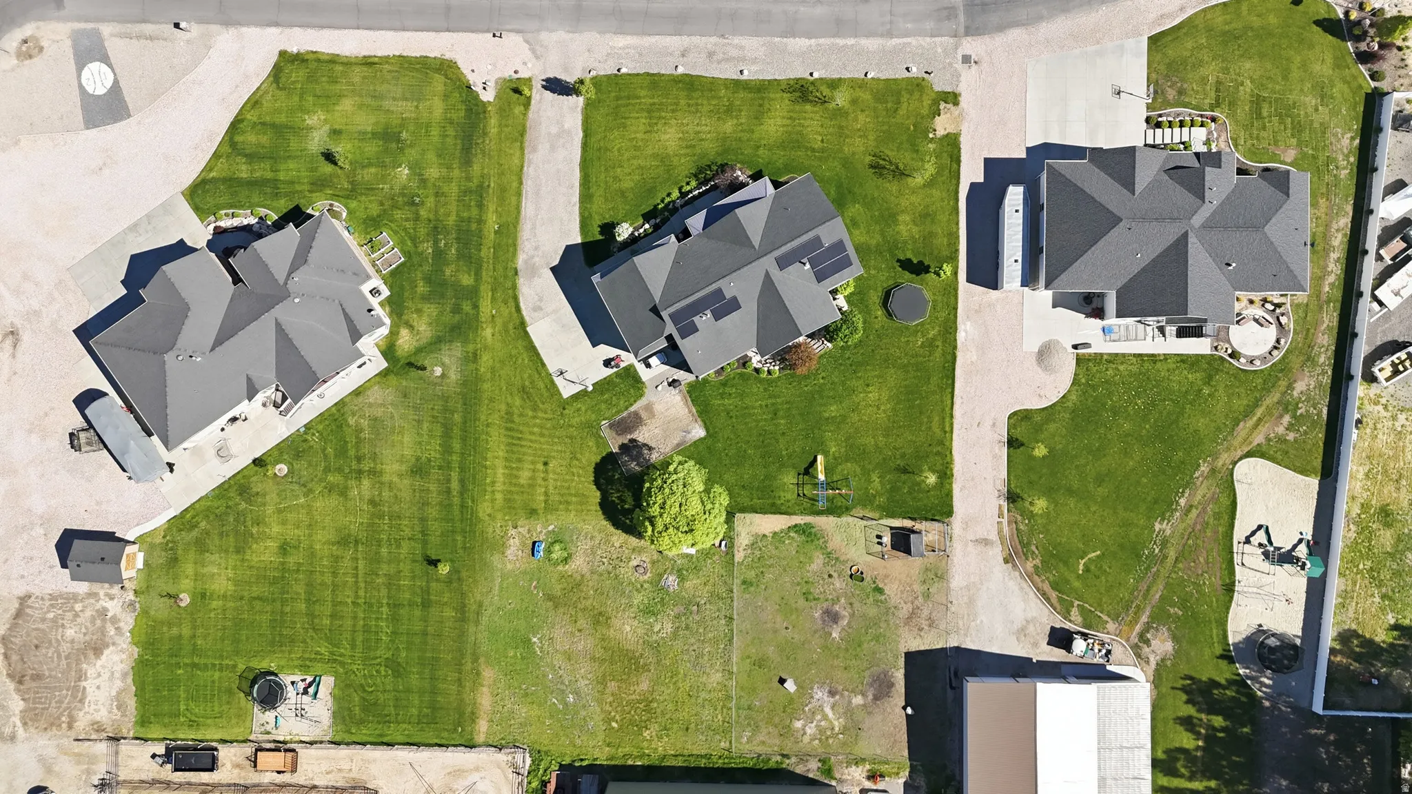 Aerial perspective showcasing multiple properties with extensive green lawns and paved driveways