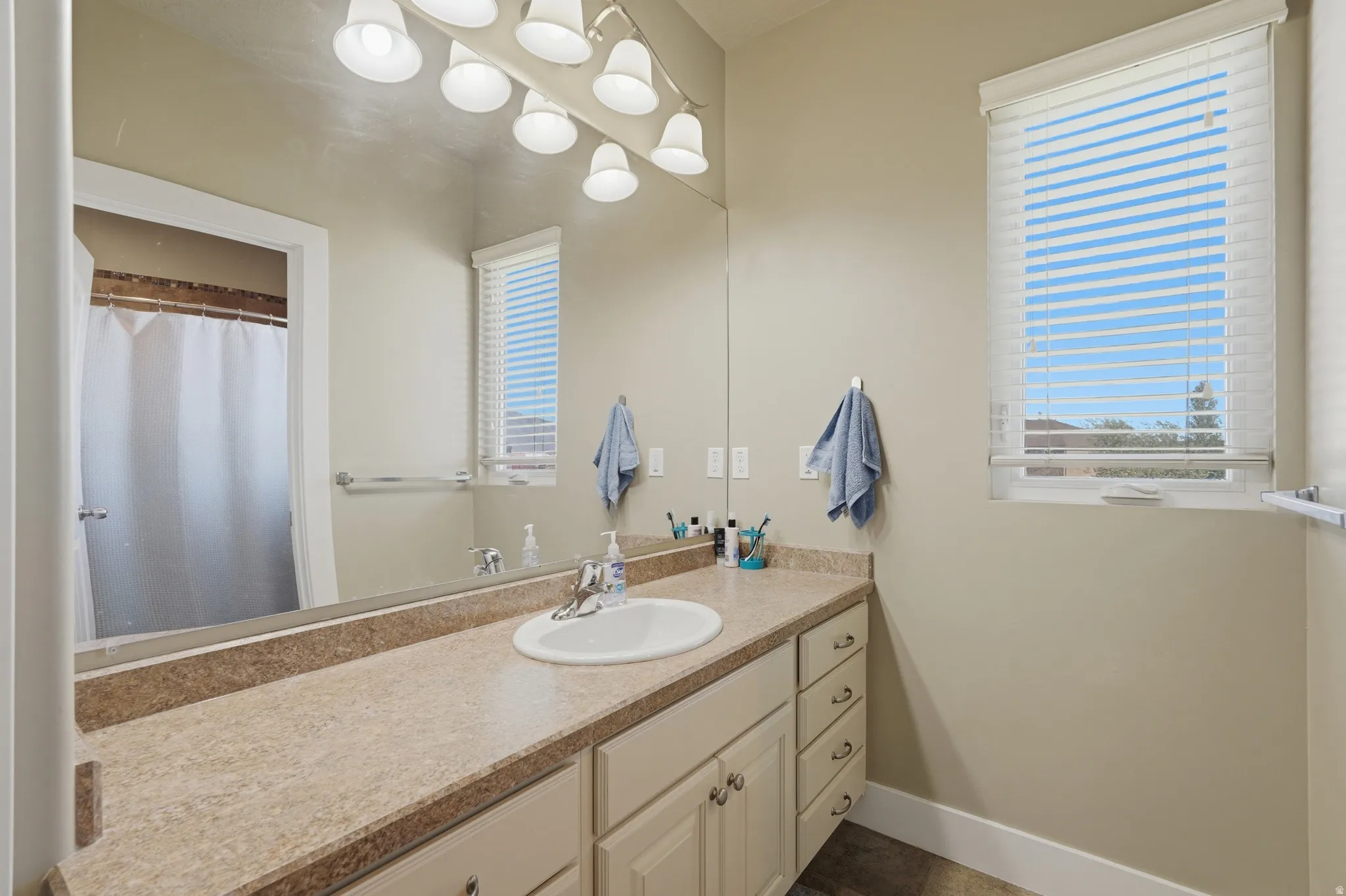 Bathroom featuring a vanity with an integrated sink, a light-toned countertop, and cabinet storage