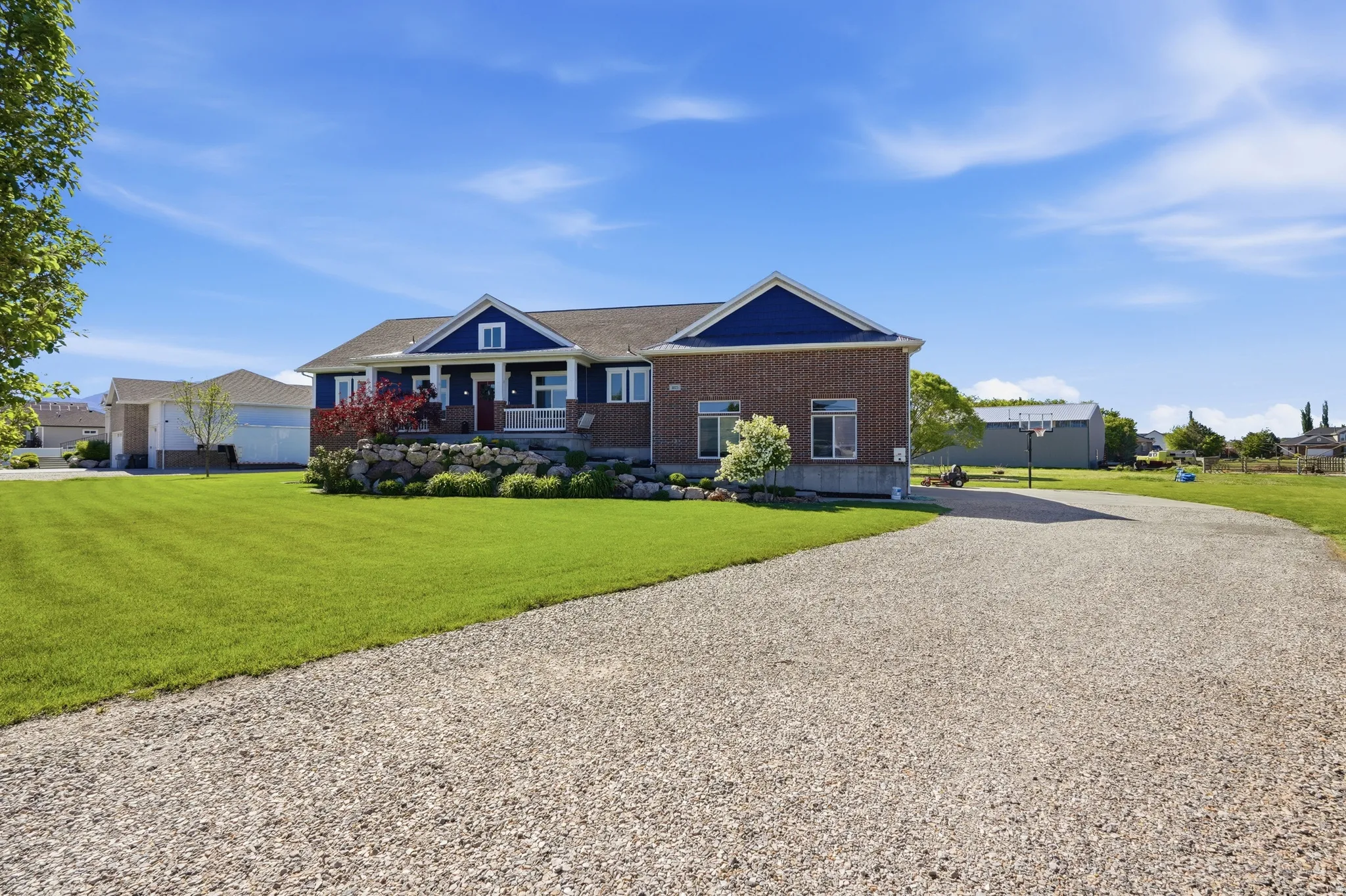 Ranch-style residence featuring a brick and blue siding exterior, a covered front porch with white columns, and a landscaped rock garden