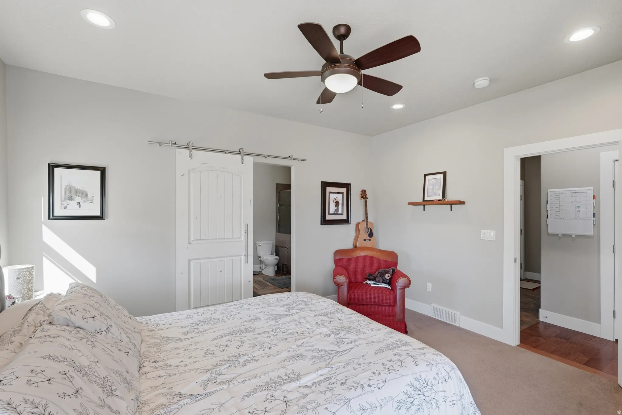 Spacious room featuring a ceiling fan with integrated lighting, recessed ceiling lights, and a barn door entry to a bathroom