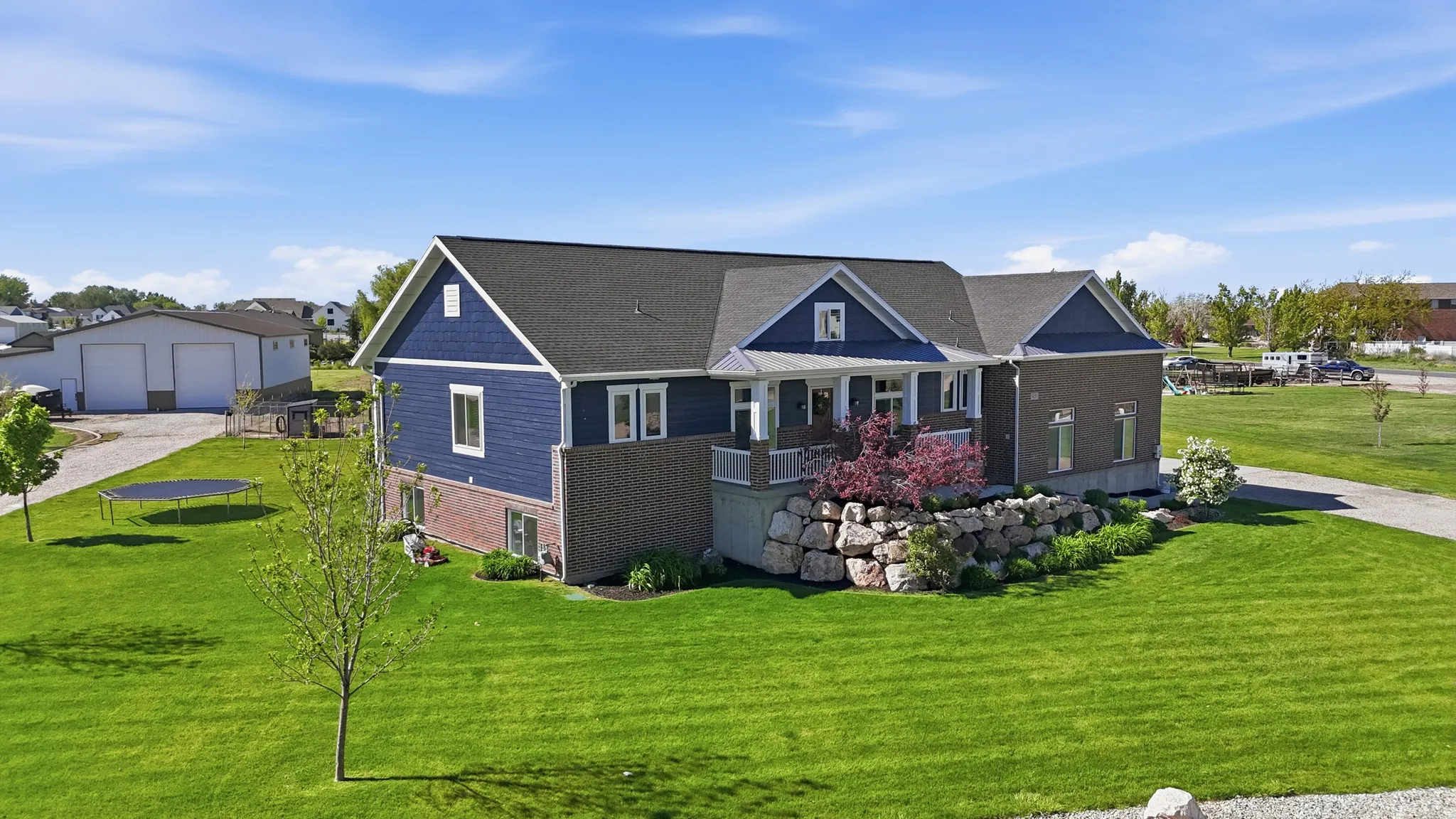 Two-story residence featuring a blue siding exterior, brick accents, and a dark shingle roof