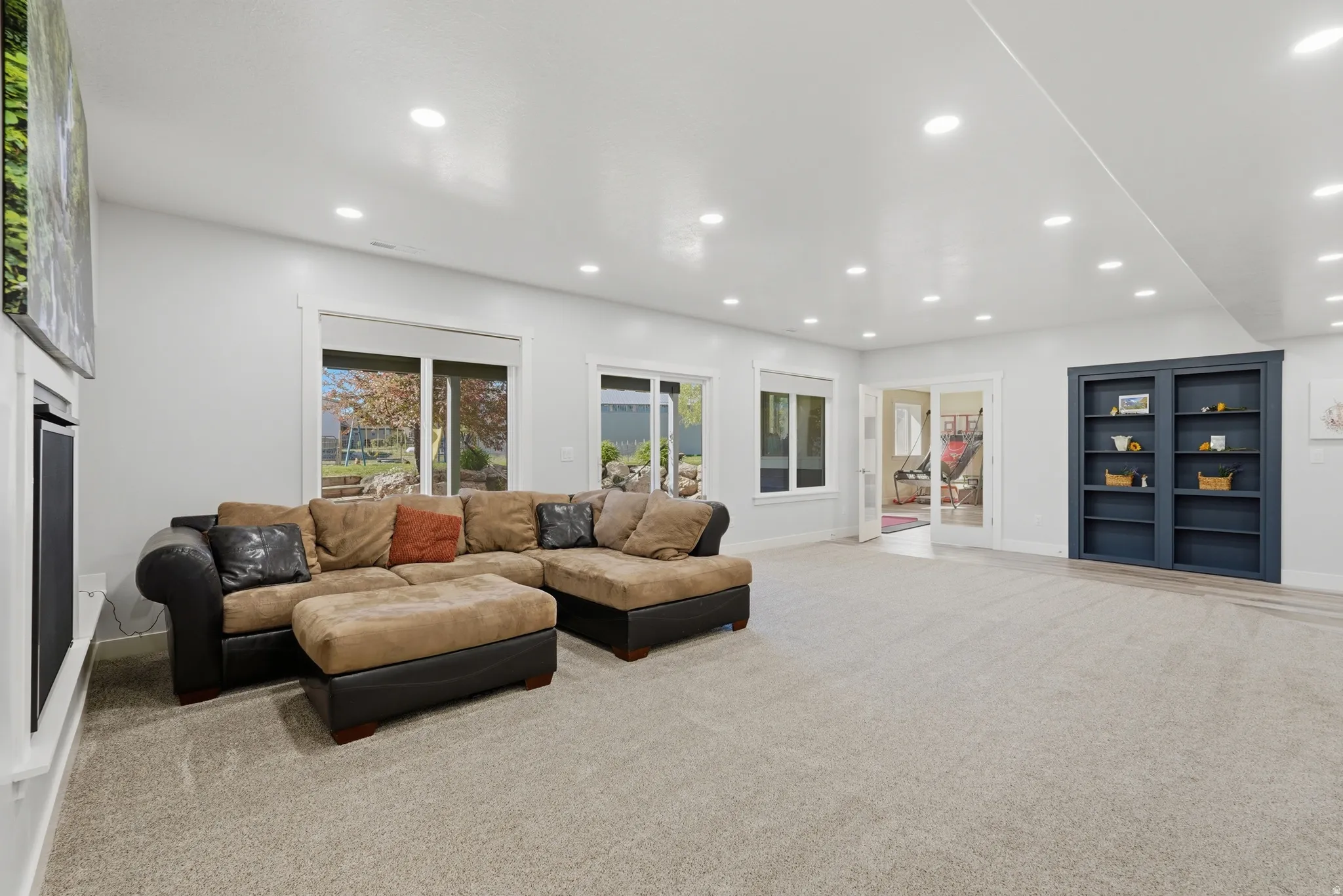 Spacious room with light-colored carpeting, multiple recessed lights, and white walls