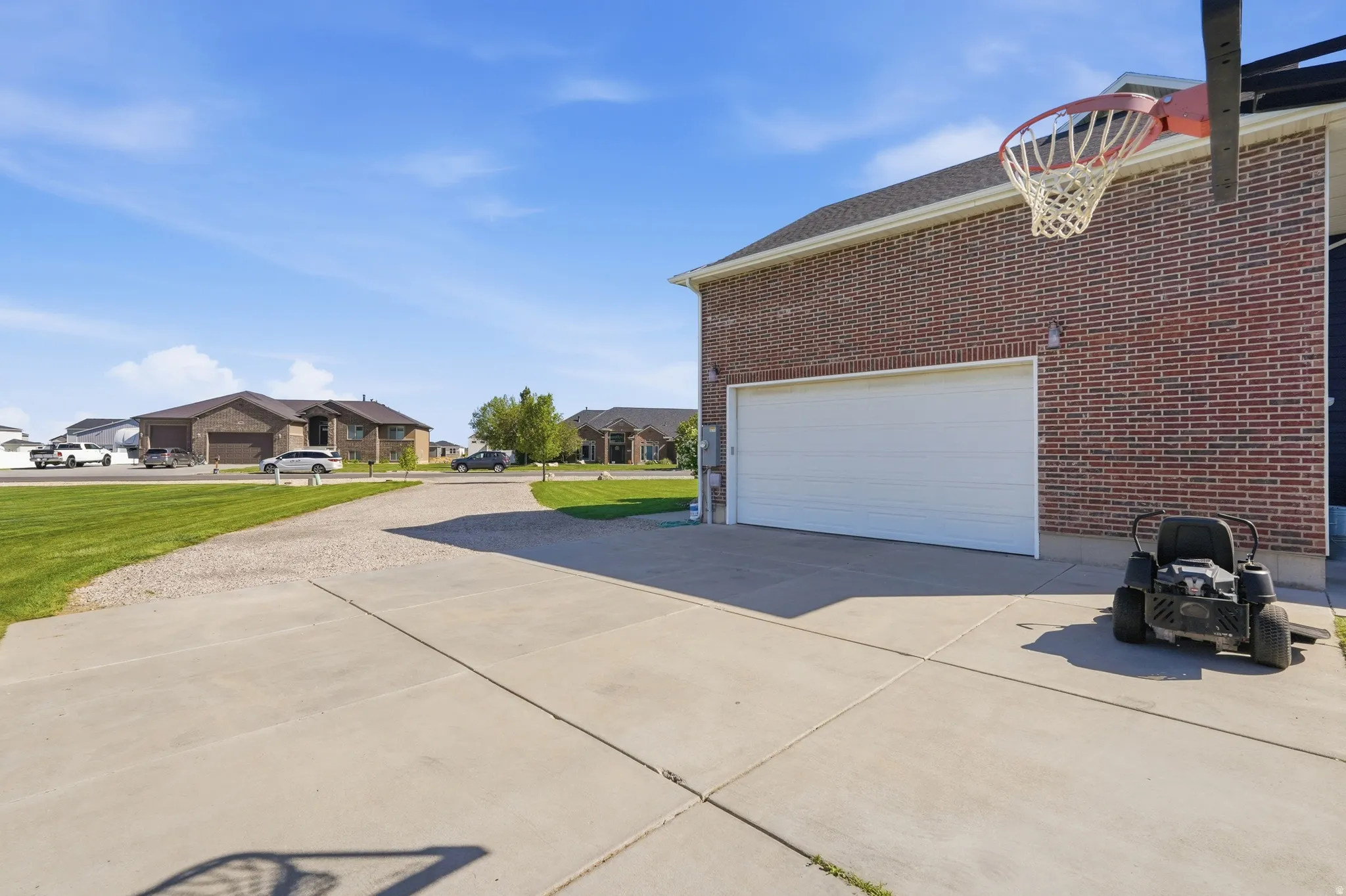 Brick exterior with a white garage door, concrete driveway, and a gravel extension