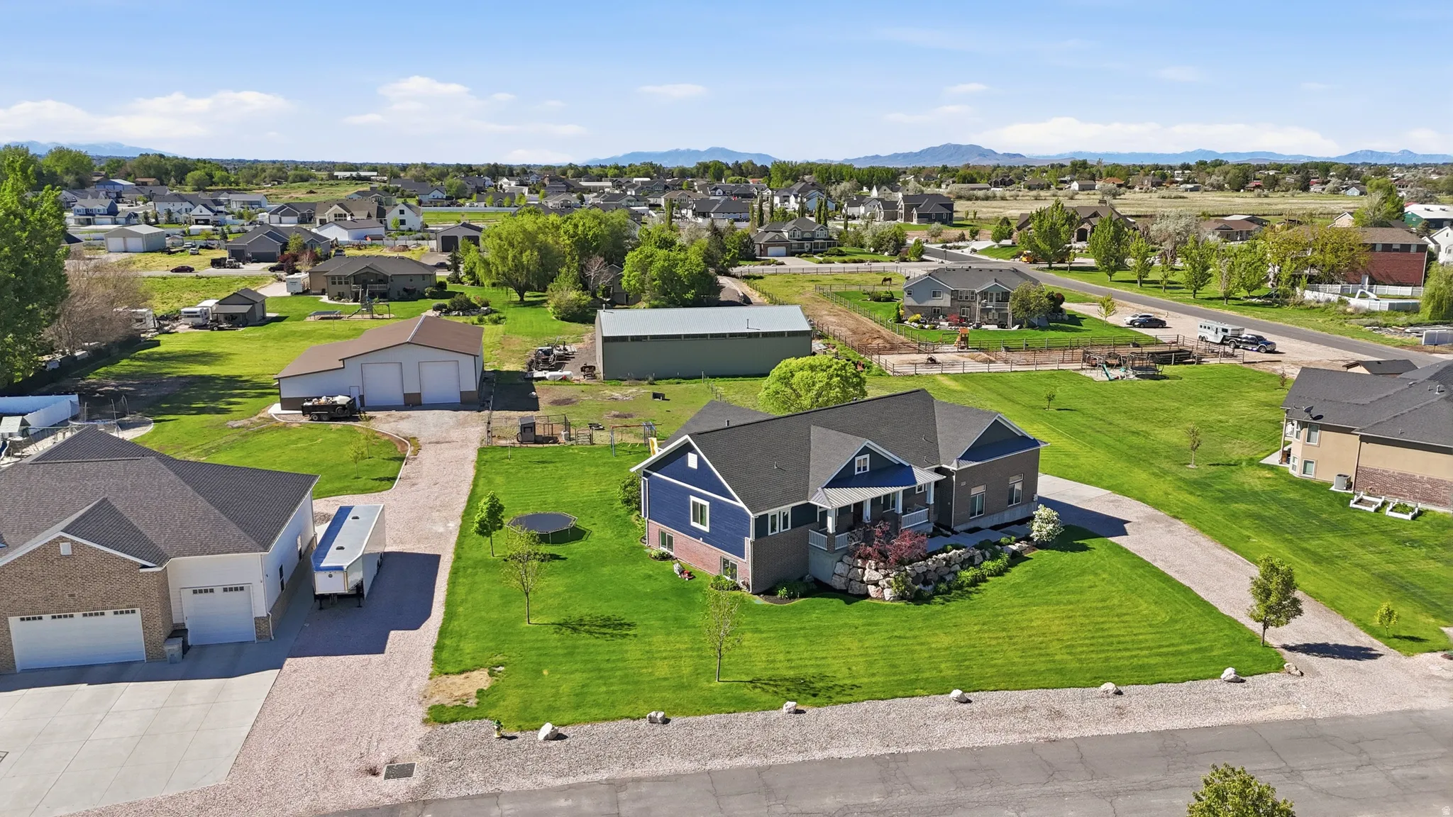 Blue siding residence with dark grey roofing, set on a large lot with expansive green lawn