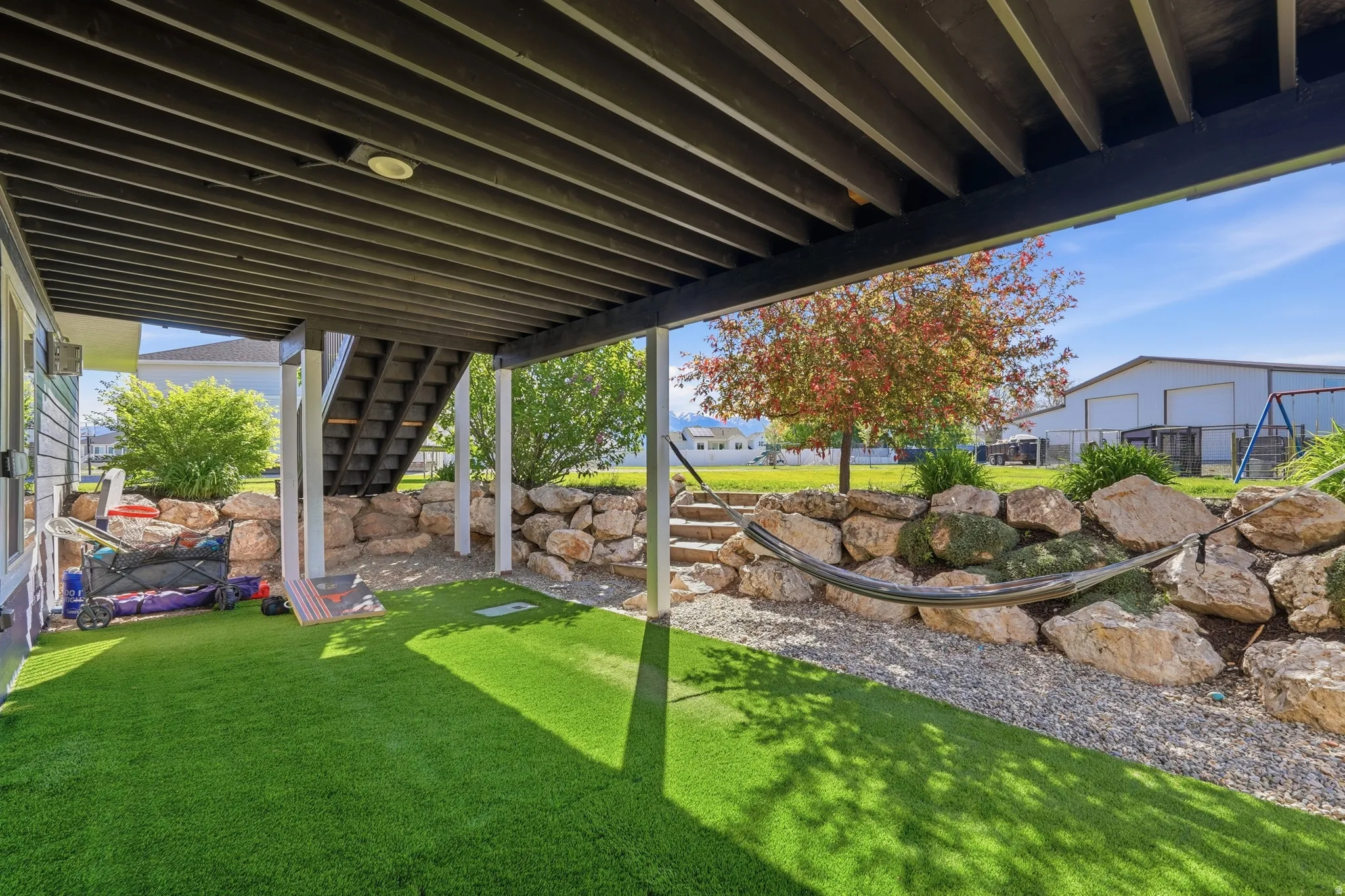 Covered outdoor patio area featuring a slatted ceiling structure and artificial turf flooring