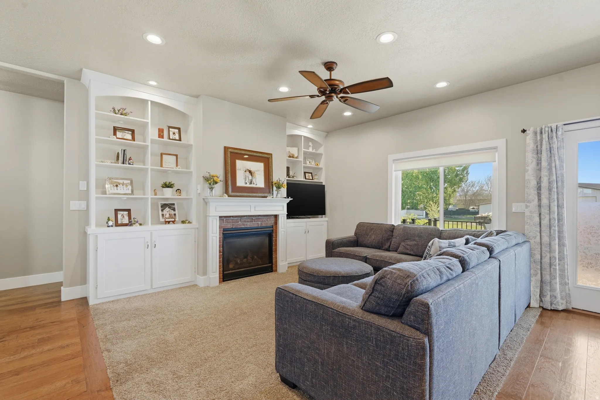 Living area featuring a gas fireplace with a brick surround, white mantel, and built-in shelving