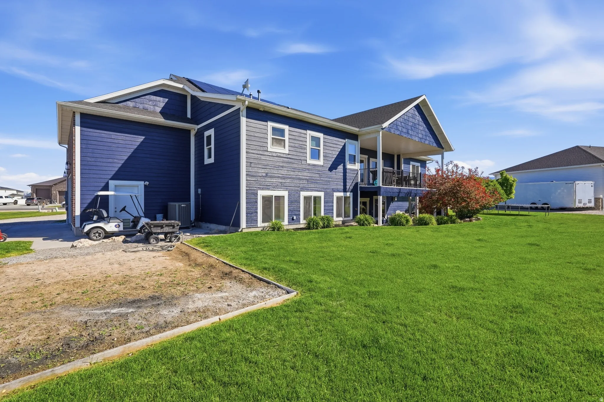 Two-story residence with dark blue horizontal siding and a covered upper-level deck