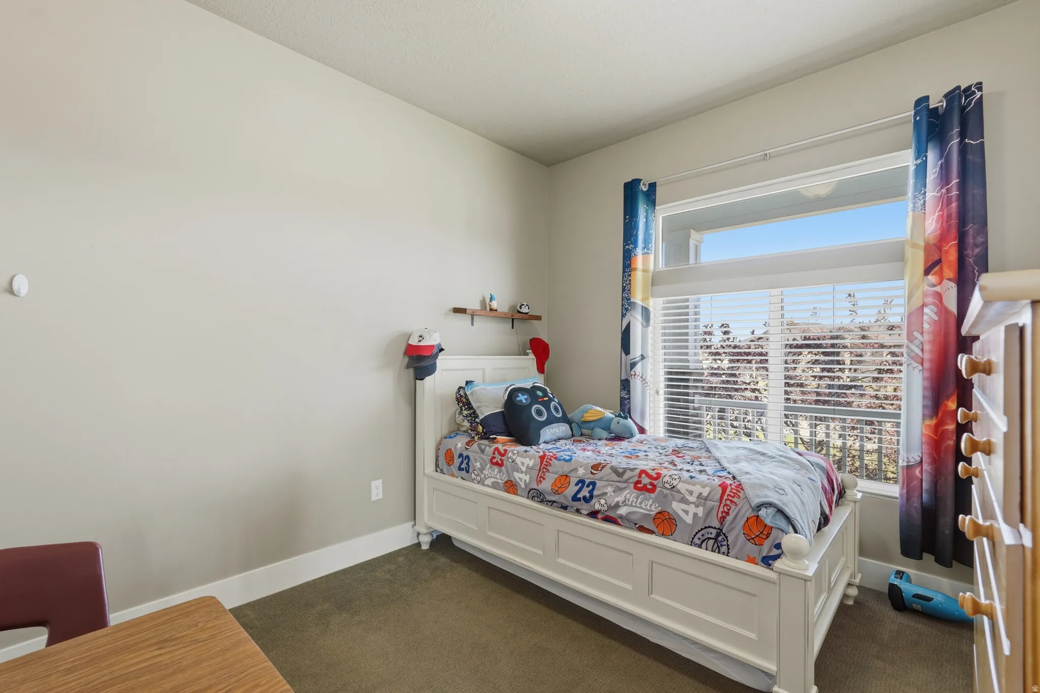 Bright room featuring a large window with horizontal blinds, neutral wall paint, and a white baseboard trim