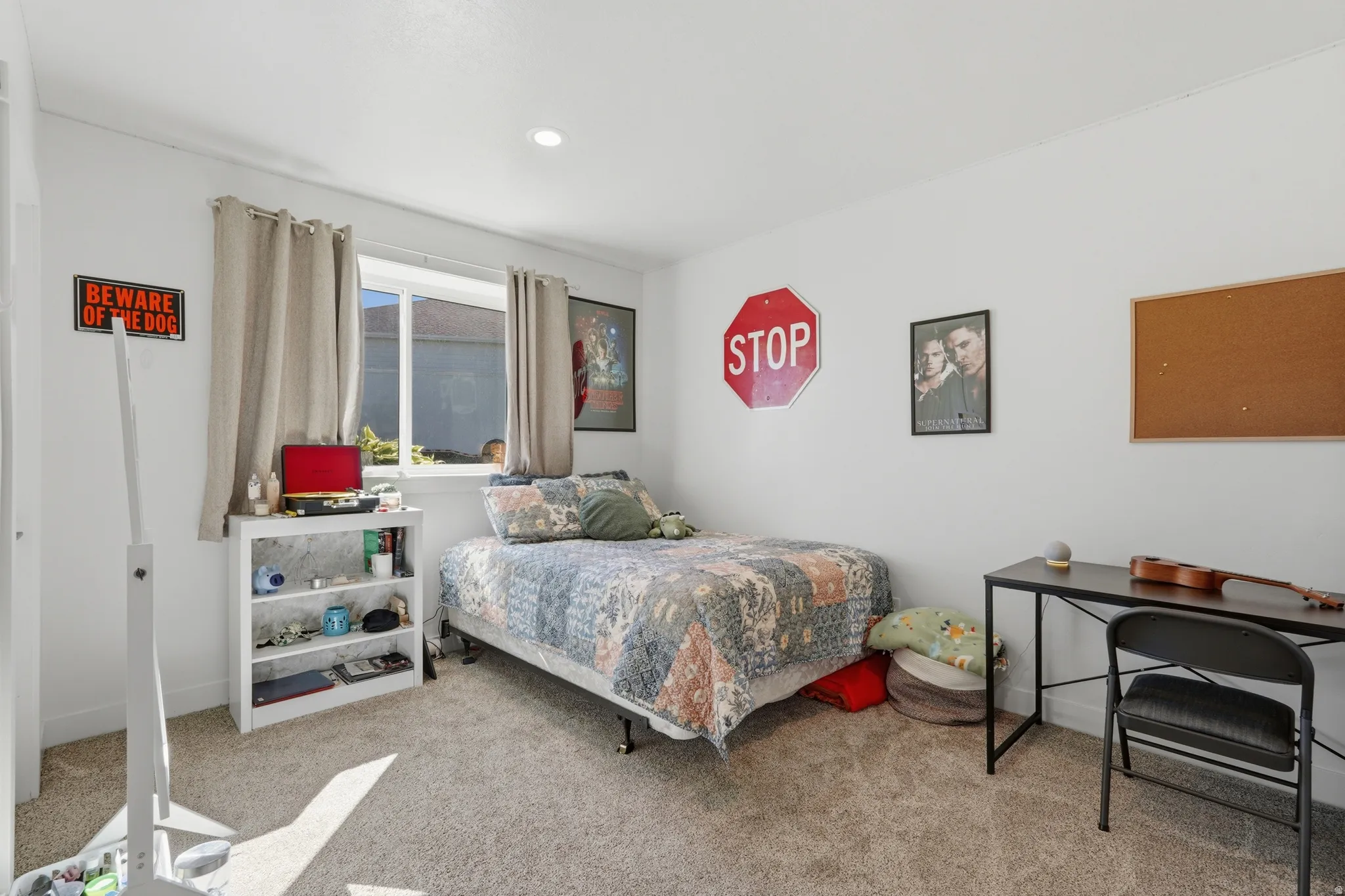 Recessed lighting illuminates this room featuring wall-to-wall carpeting and a window with natural light
