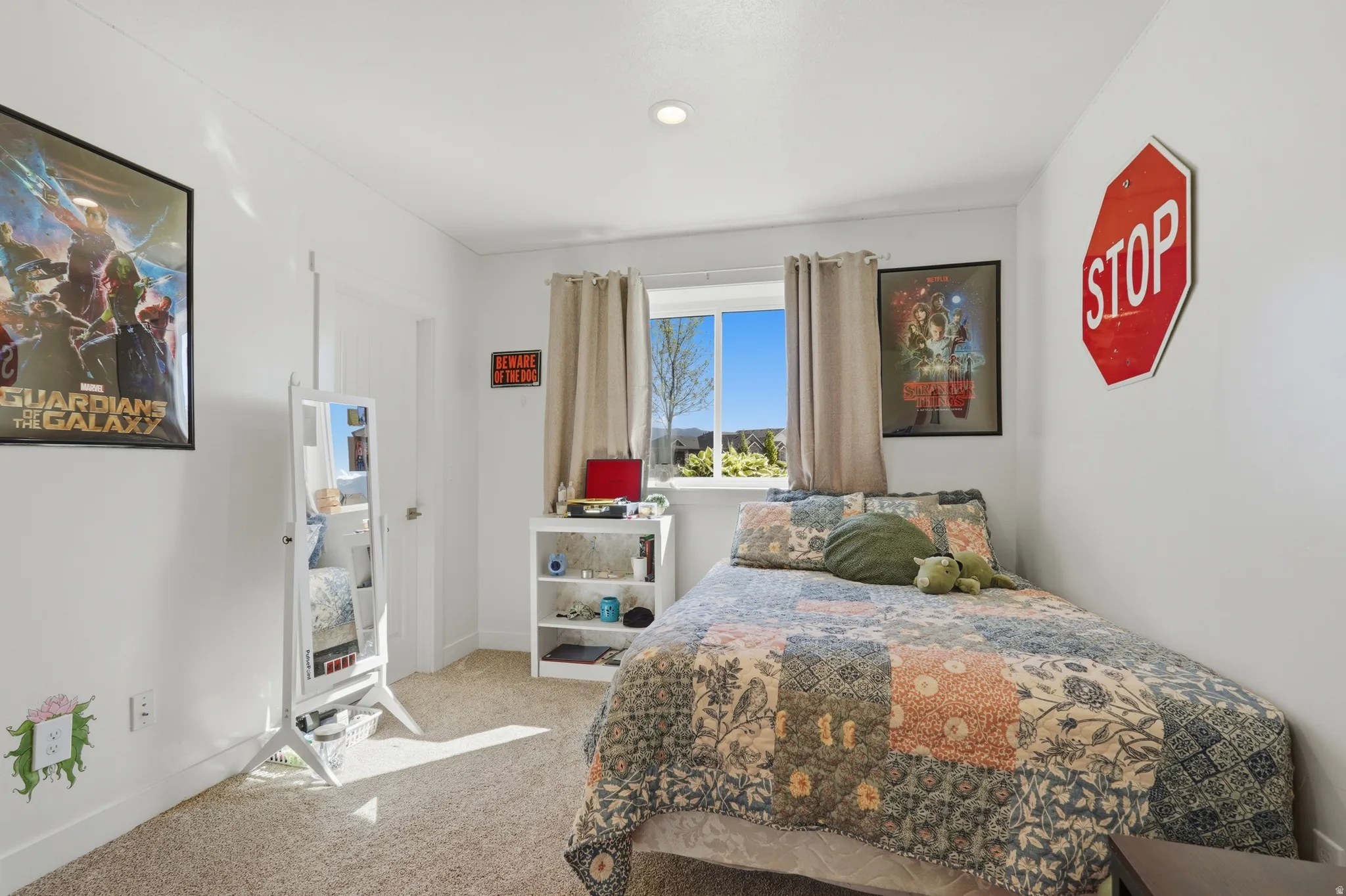 Carpeted room with a window featuring light-colored drapes, white walls, and a recessed ceiling light