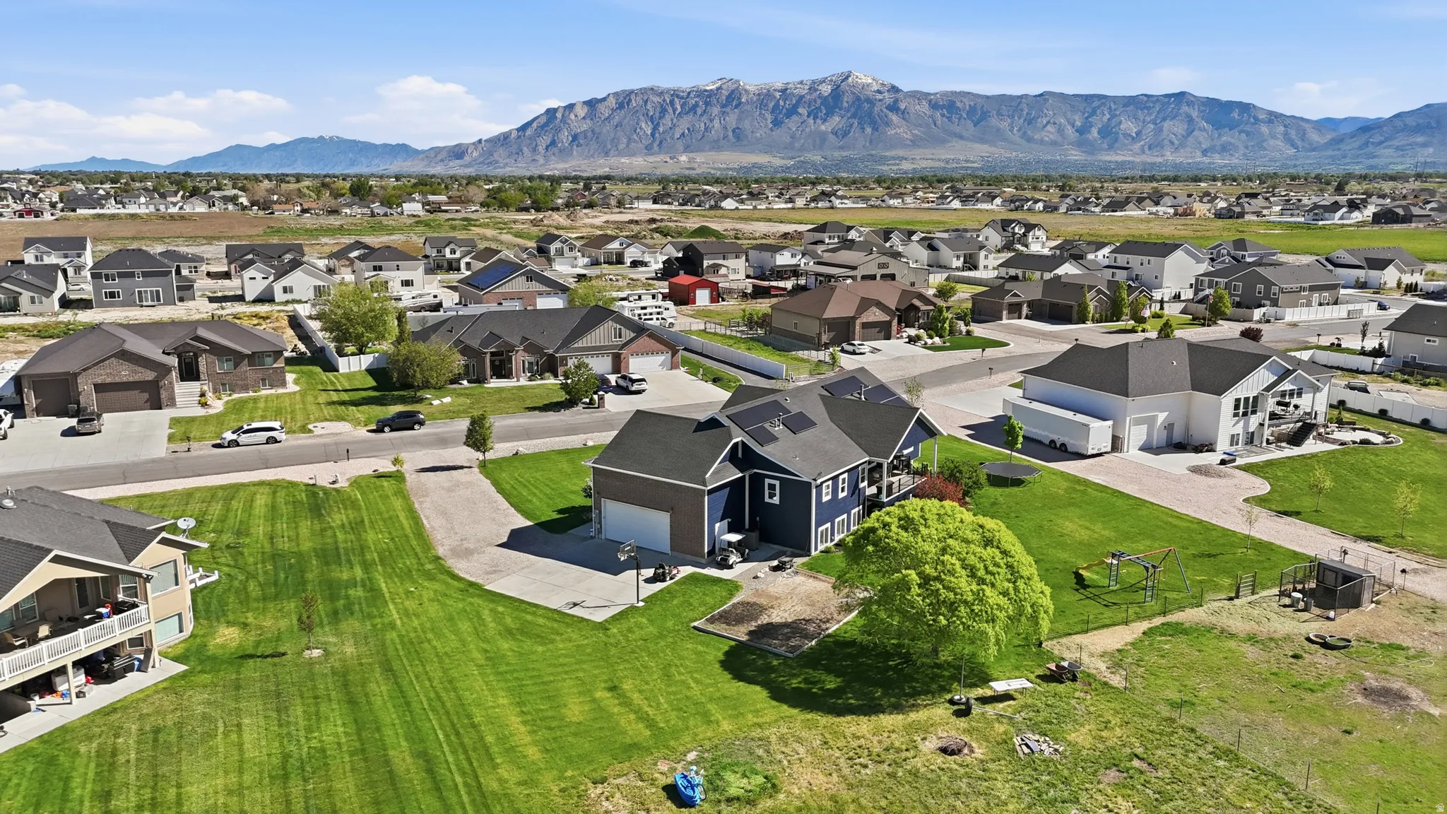 Suburban setting featuring a spacious property with a blue-sided residence, attached garage, and a lush green lawn
