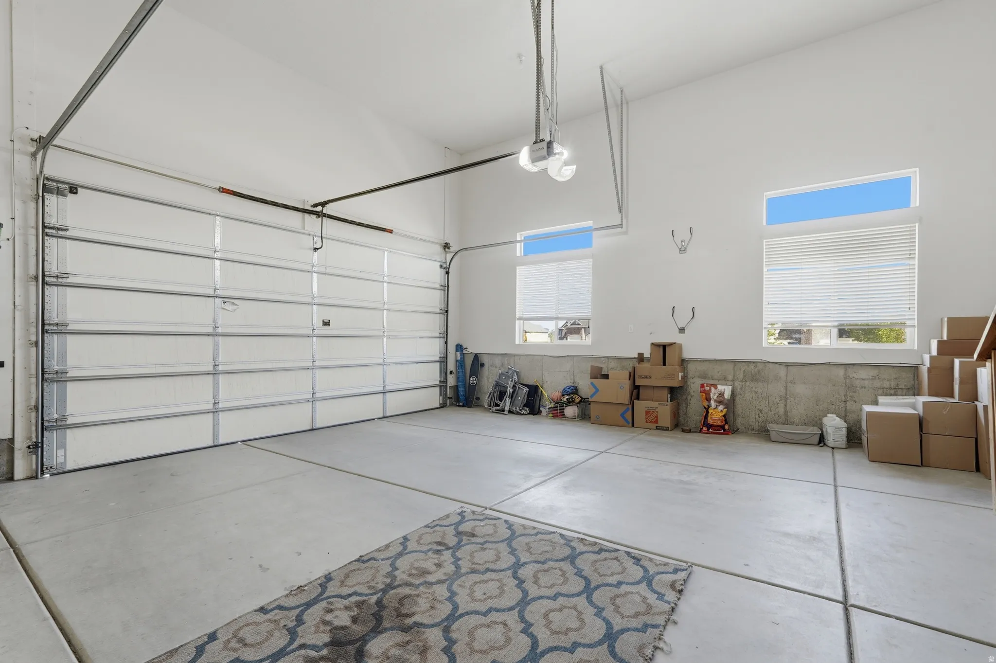 Spacious garage featuring a large automatic overhead door, high ceilings, and concrete flooring