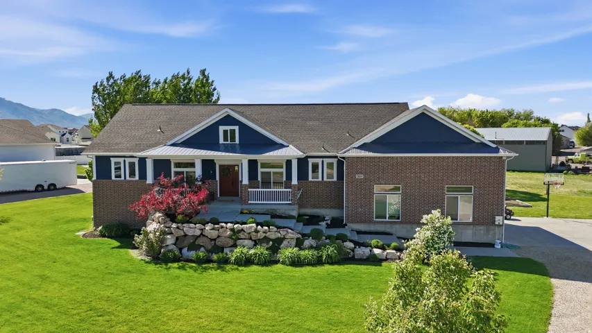 Brick and siding exterior featuring a covered front porch with white columns, a dark shingle roof, and an expansive green lawn