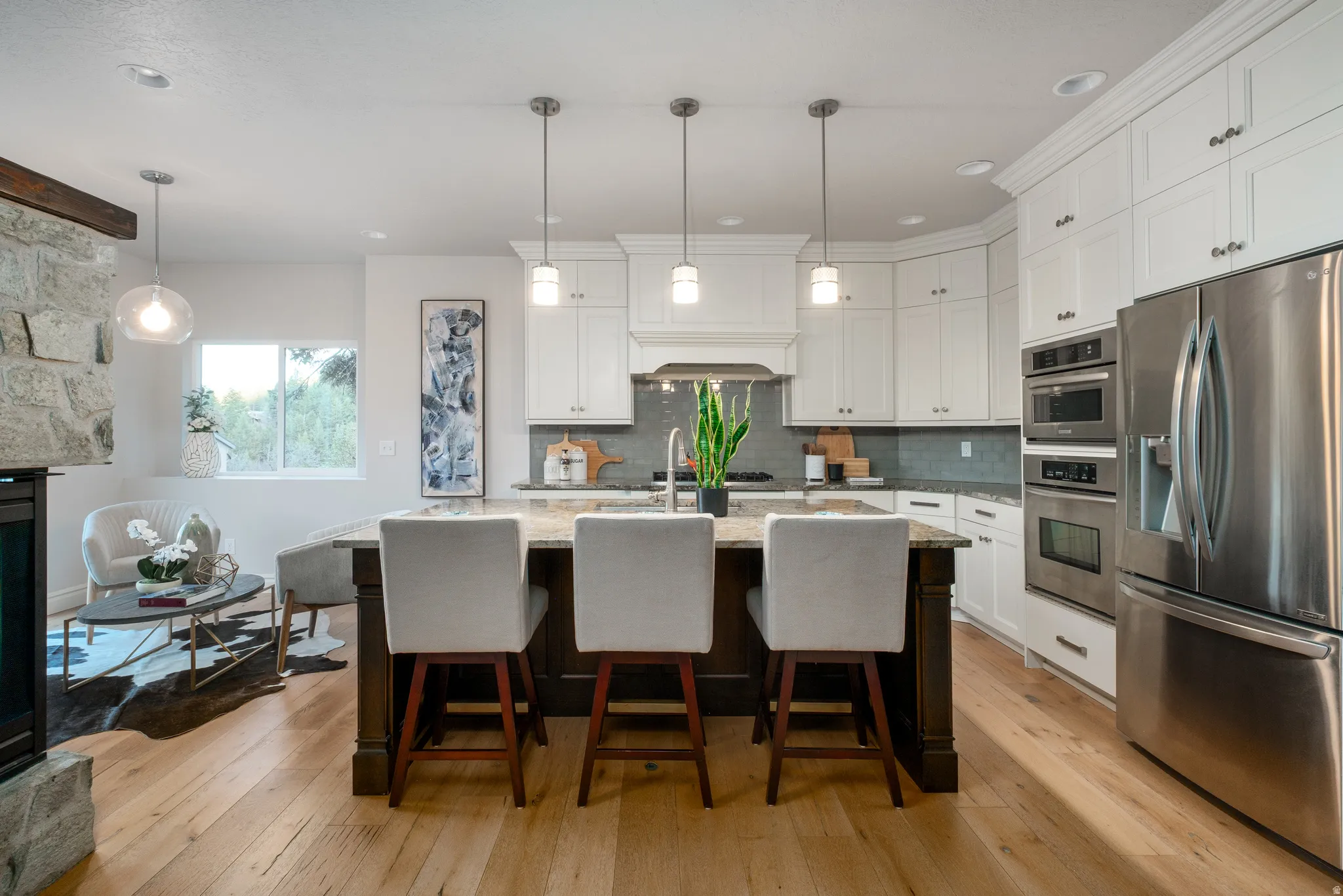 Open-concept kitchen featuring white shaker cabinetry, stainless steel appliances, a dark wood-finish island with seating, and wood-finish flooring