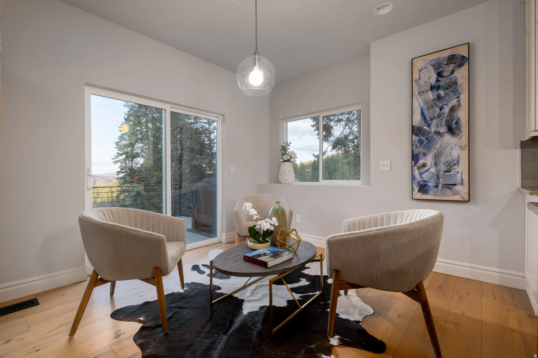 Room featuring wood-finish flooring, a contemporary pendant light fixture, and large sliding glass doors