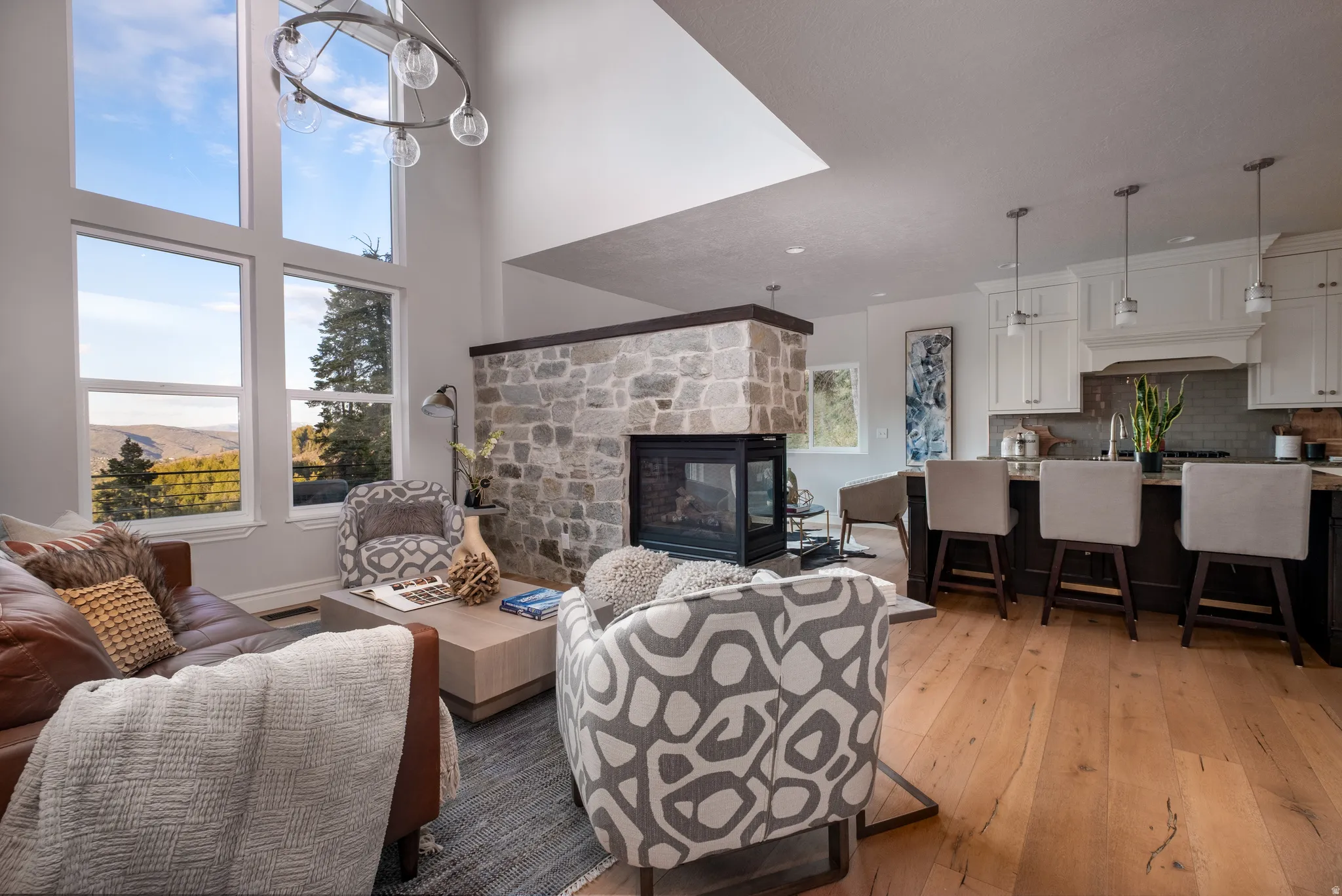 Open-concept living space featuring high ceilings, wood-finish flooring, and an integrated stone fireplace