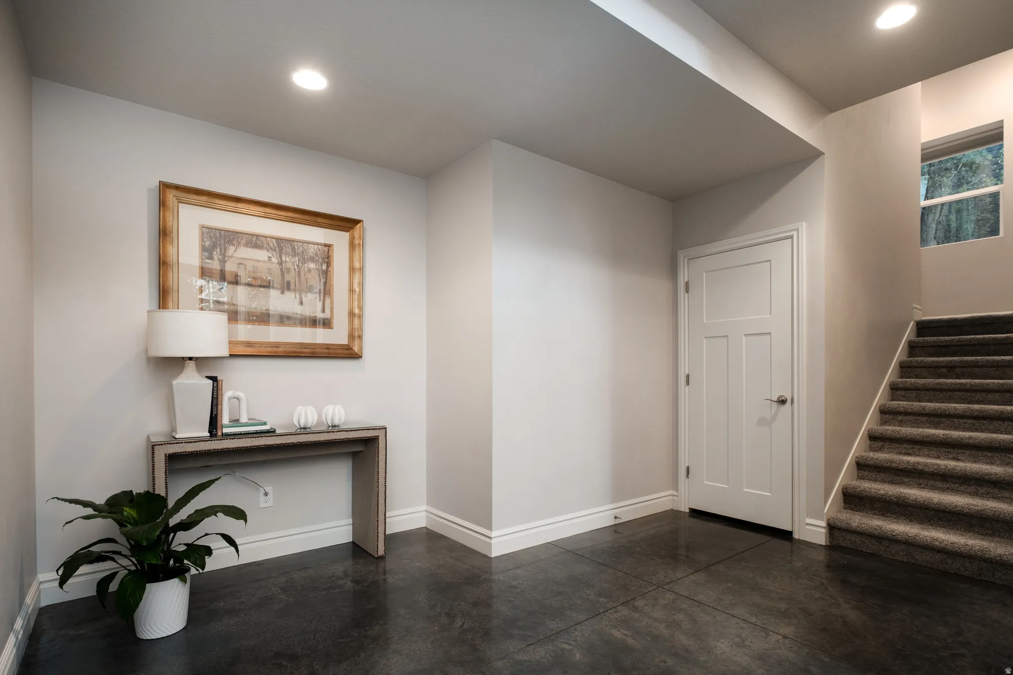 Foyer featuring dark stone-finish flooring, recessed lighting, a paneled interior door, and a carpeted staircase with a window