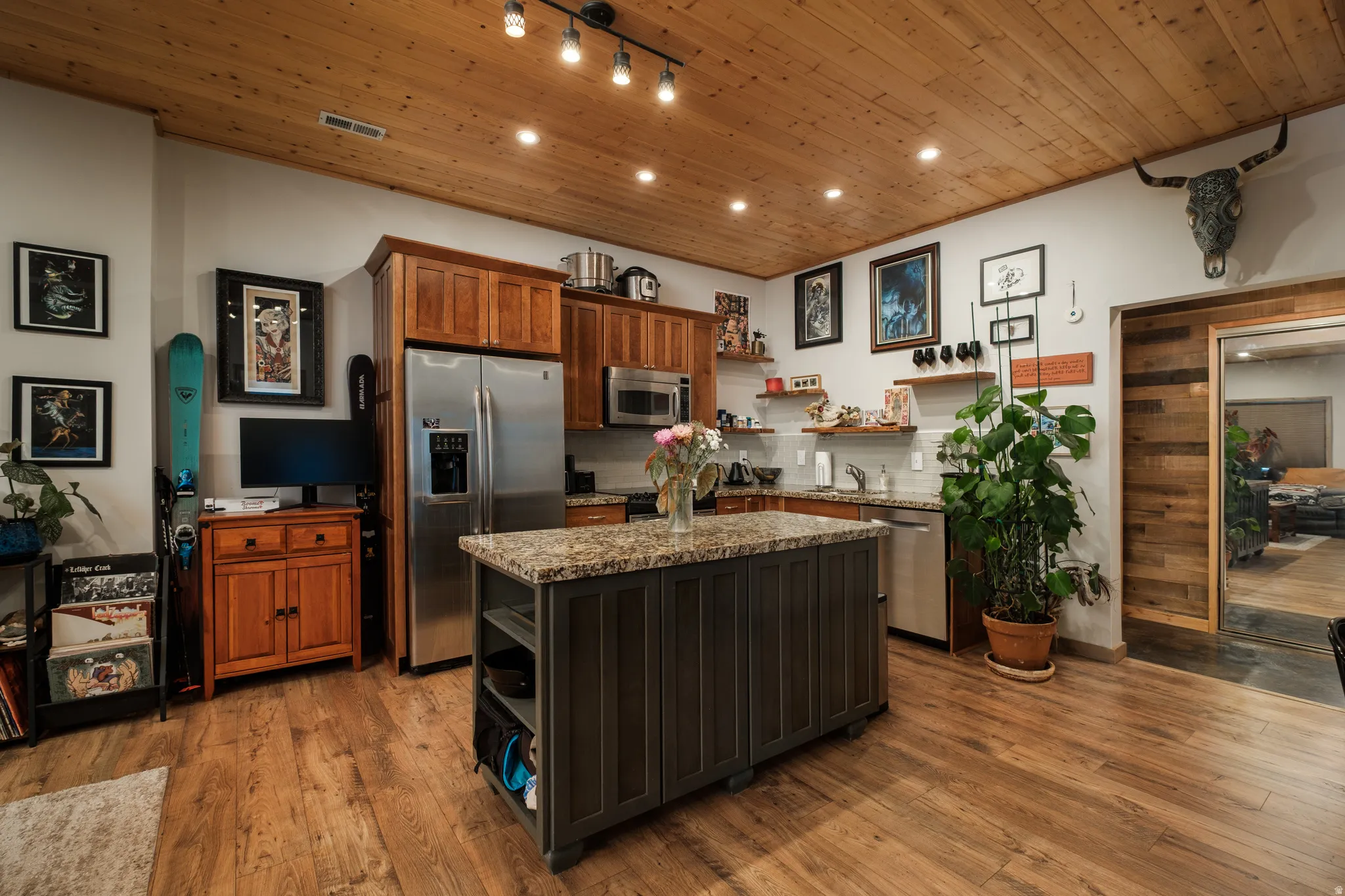 Kitchen featuring wood-finish flooring, wood plank ceiling, track lighting, and a kitchen island with a stone countertop