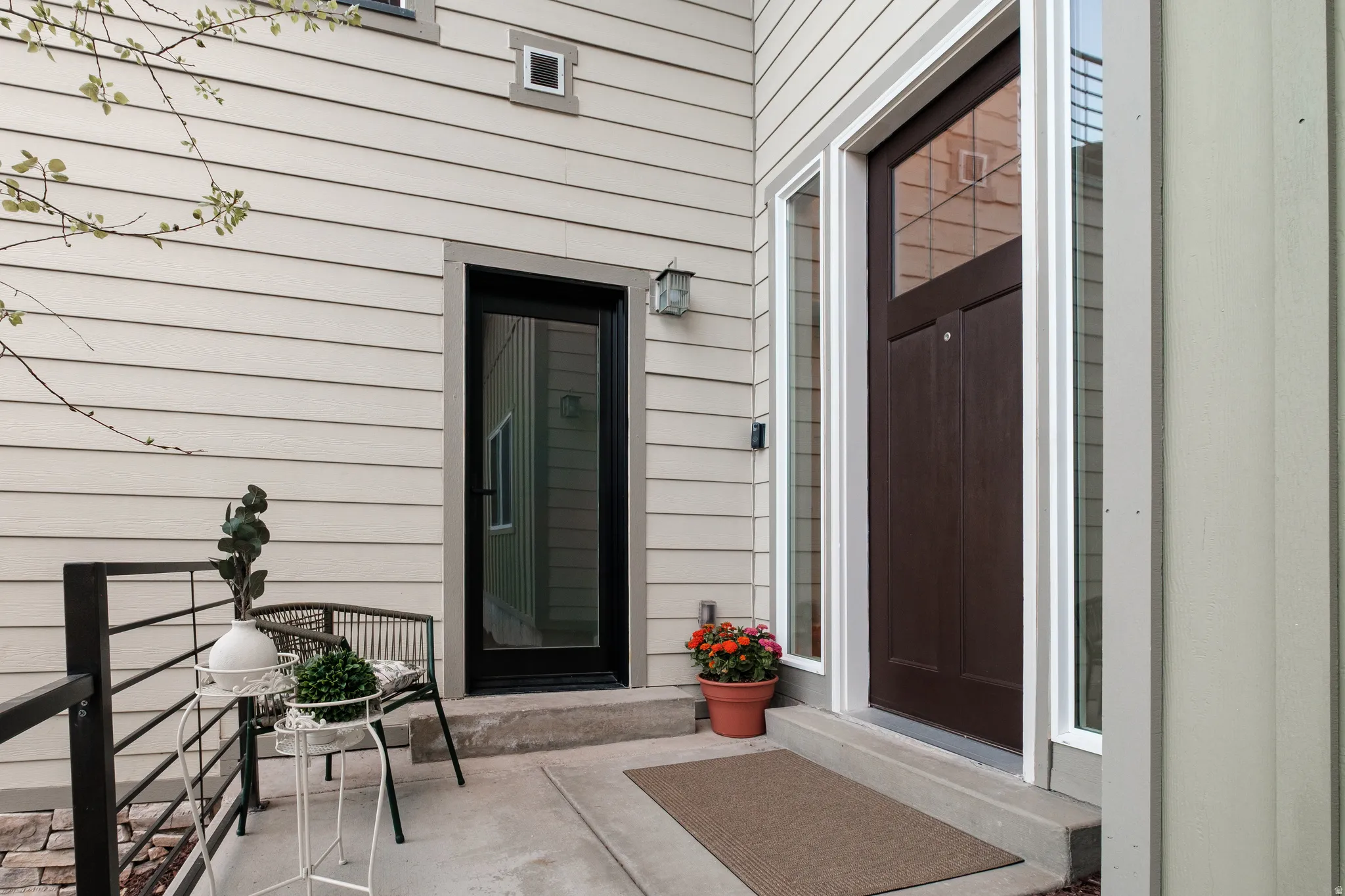 Entryway featuring a dark wood-finish door with transom window and side lights, light-toned siding, and a concrete landing