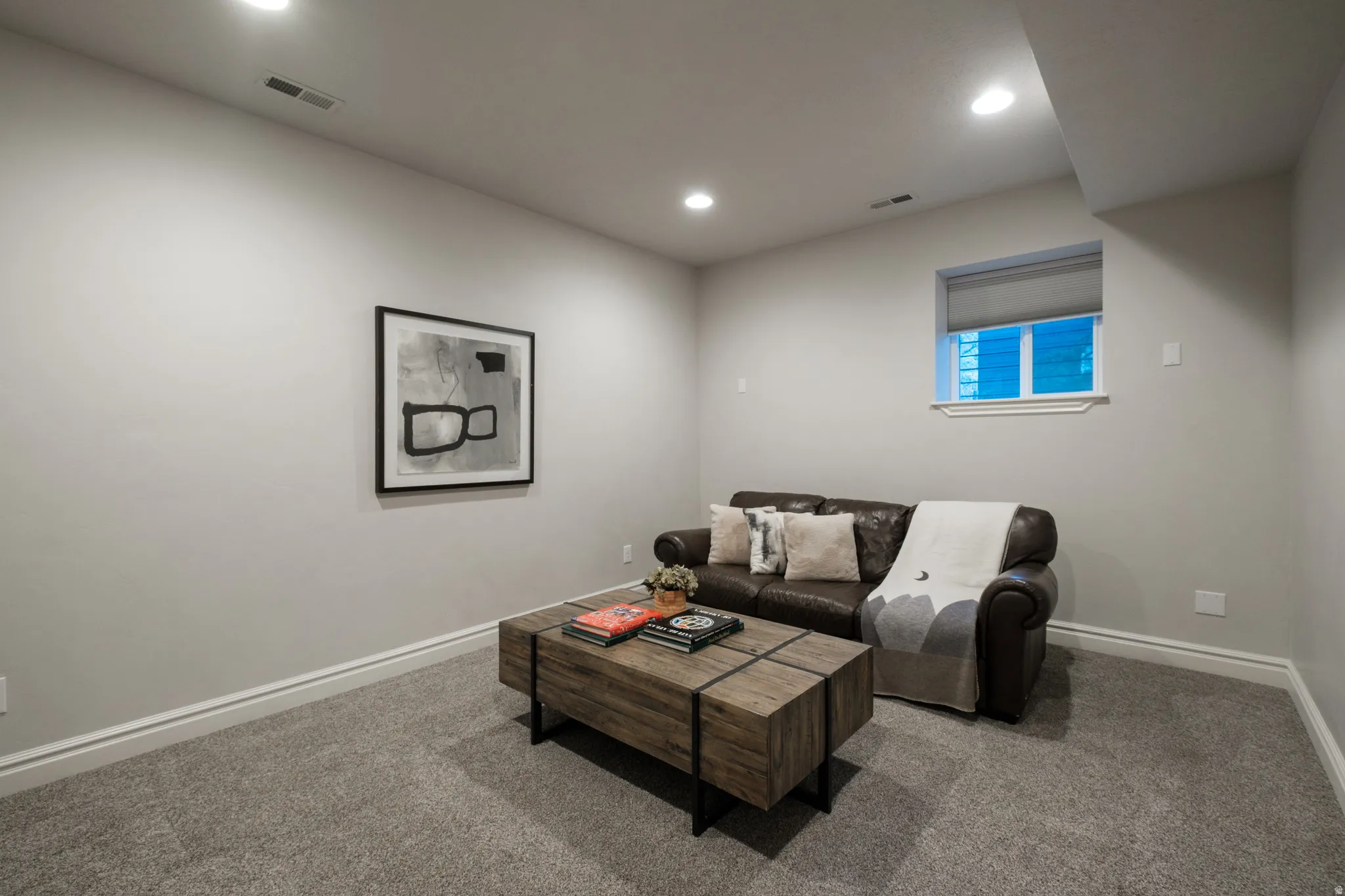 Carpeted room featuring recessed lighting, a window with a roller blind, and white baseboard trim