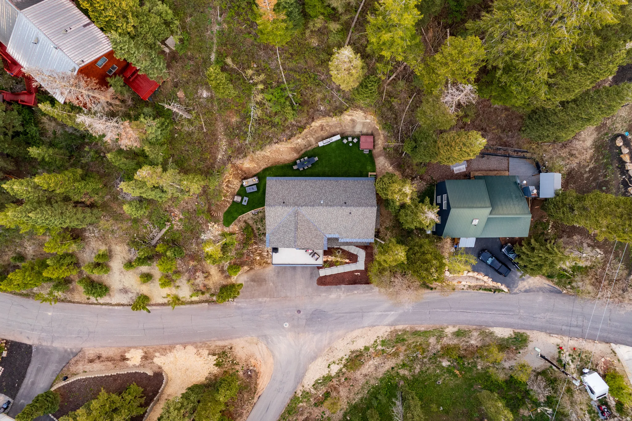 Gable rooflines and an asphalt shingle roof characterize this property, surrounded by mature trees and natural landscaping