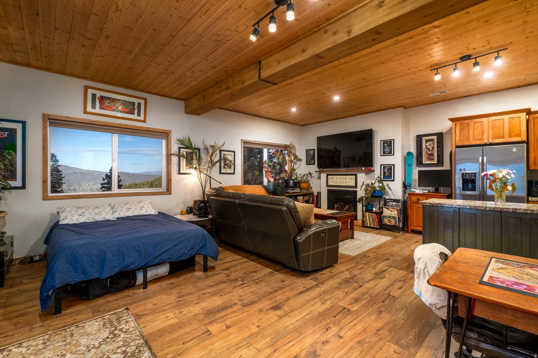 Spacious living area featuring wood-finish flooring, a natural wood paneled ceiling, and exposed ceiling beams