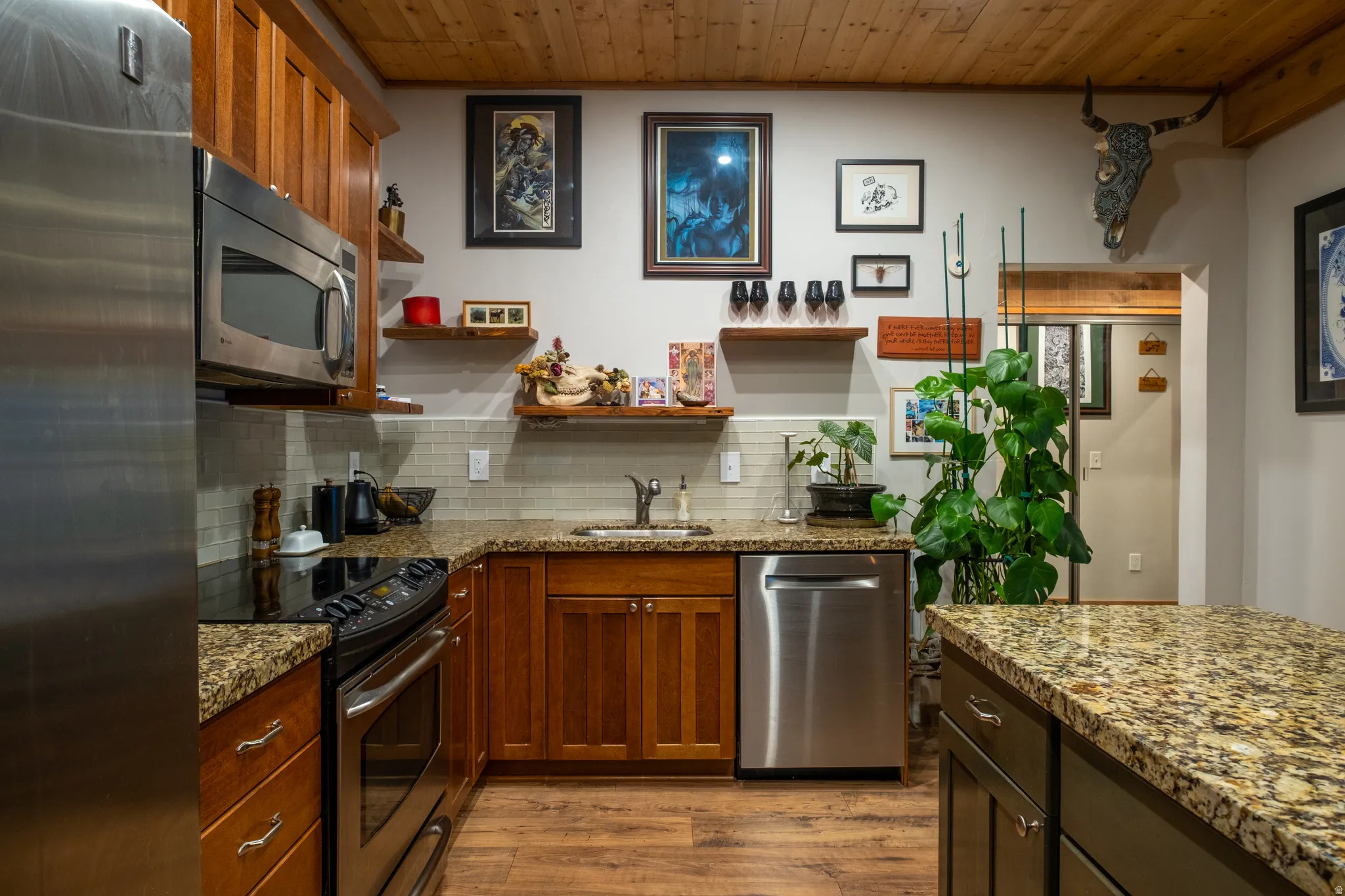 Kitchen featuring wood-finish flooring, wood cabinetry, granite countertops, and stainless steel appliances