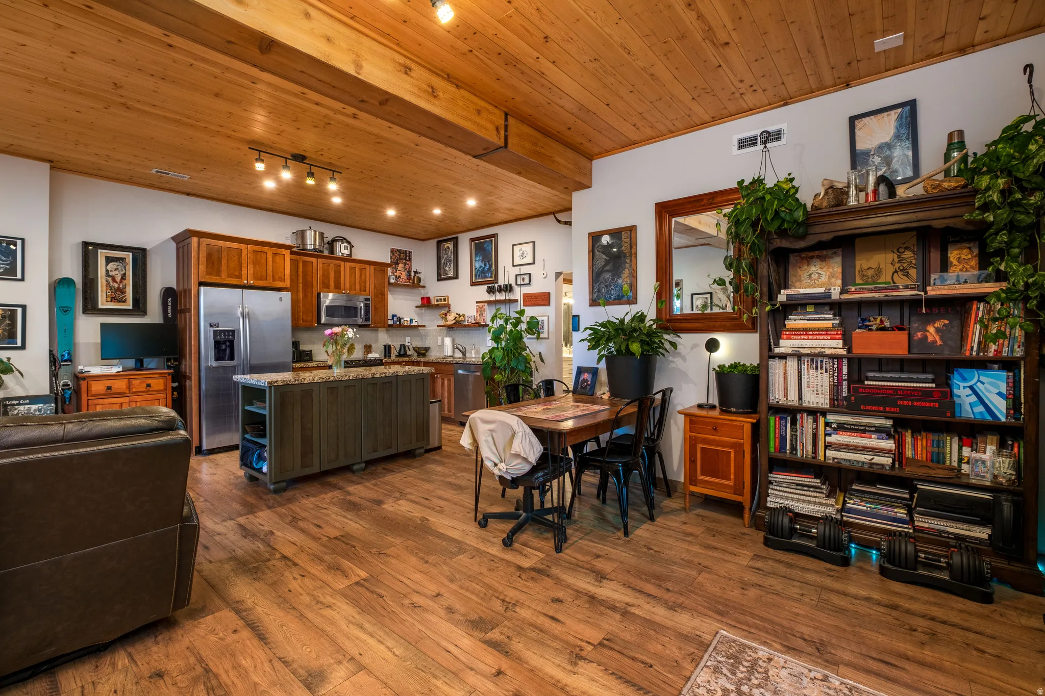 Open-concept living area with wood-finish flooring, a wood-paneled ceiling with exposed beams, and track lighting