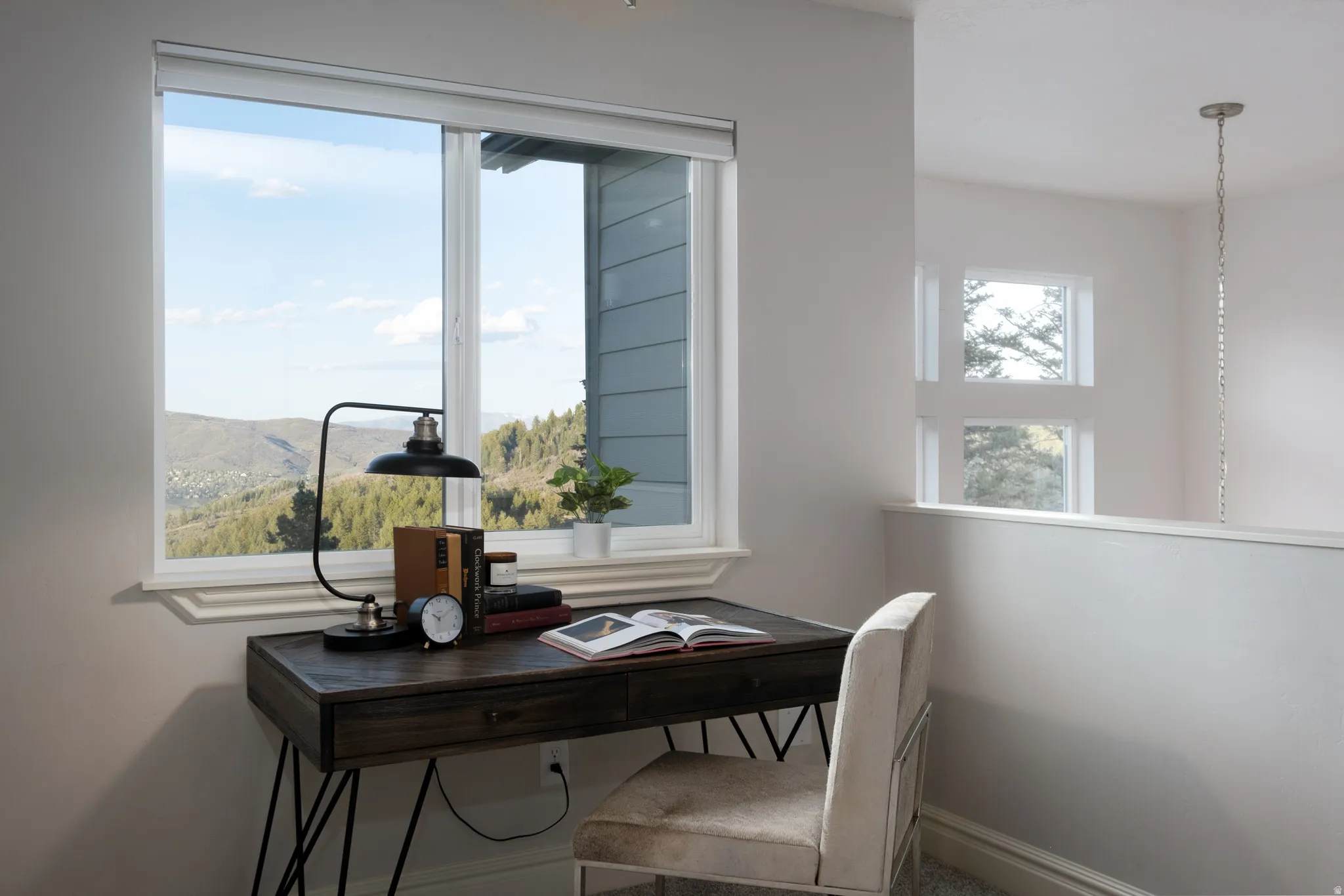 Bright interior space featuring a large window with white trim, offering expansive views of distant hills and trees