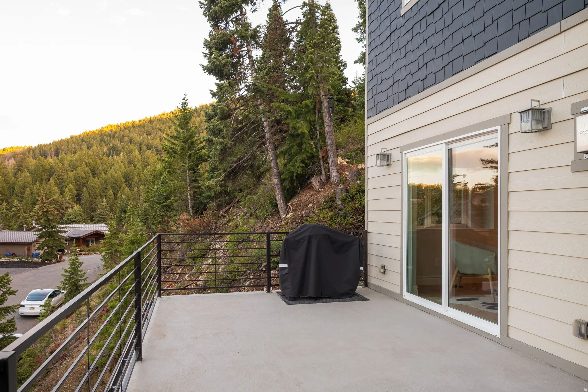 Exterior balcony featuring a concrete surface, black metal railings, and dual outdoor wall lanterns