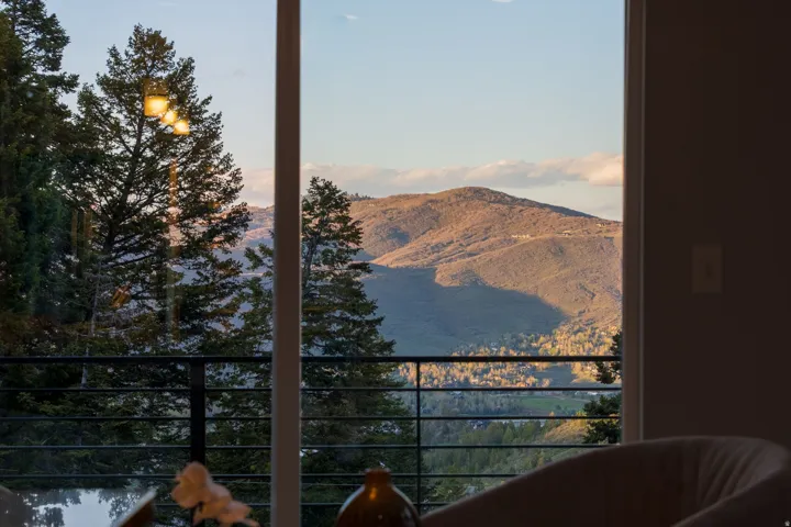 Floor-to-ceiling windows framing mountain and forest scenery