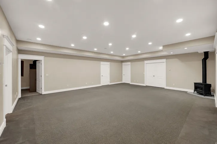 Spacious room featuring neutral paint, recessed lighting, and a cast iron stove with a dark flue
