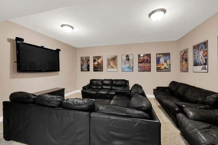 Spacious media room featuring wall-mounted television, recessed ceiling lights, and light-toned wall paint
