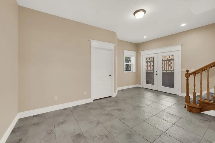 Spacious room featuring gray tile flooring, a white paneled door, and French doors with decorative glass panels